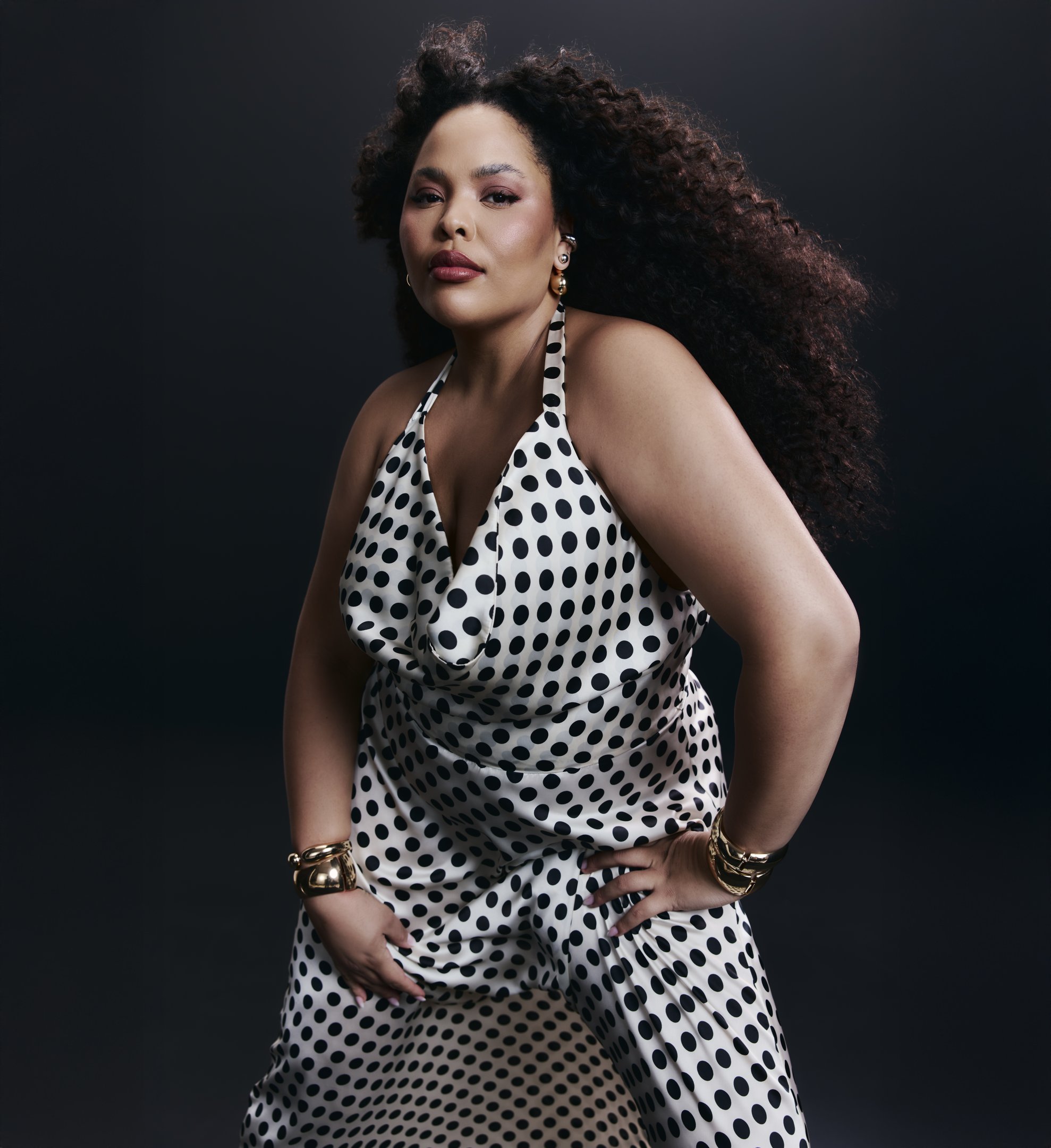 Loira usando vestido de bolinhas preto e branco, com cabelo cacheado.