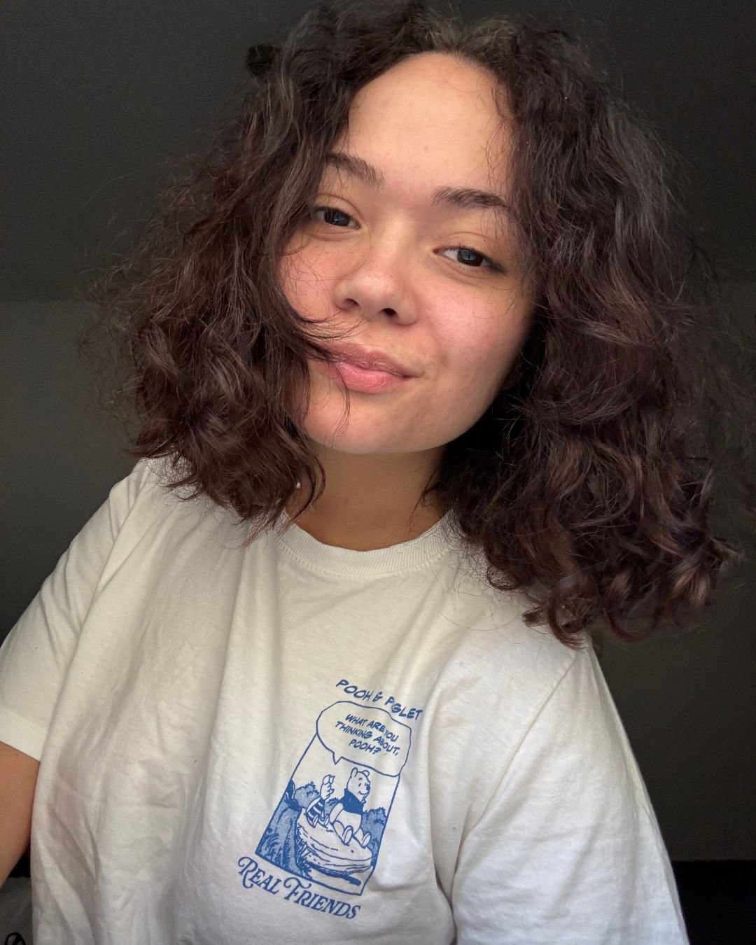 stefany com camiseta branca antes de usar a linha para cabelos cacheados
