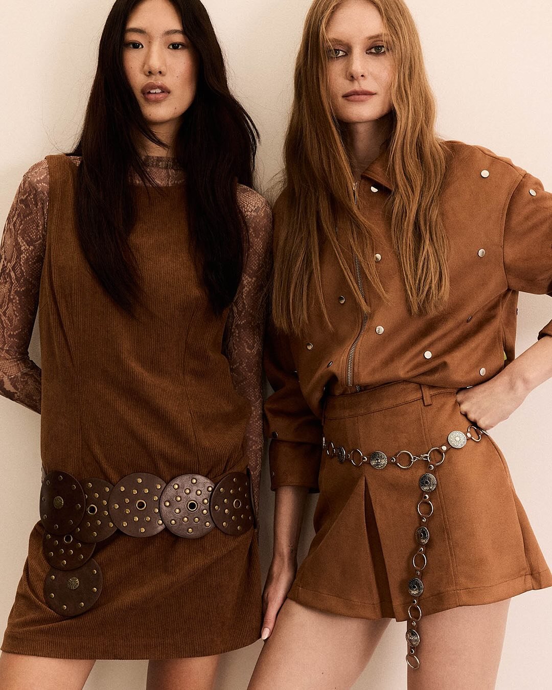 Duas modelos em roupas de outono com cintos decorativos, comemorando 60 anos da Renner.