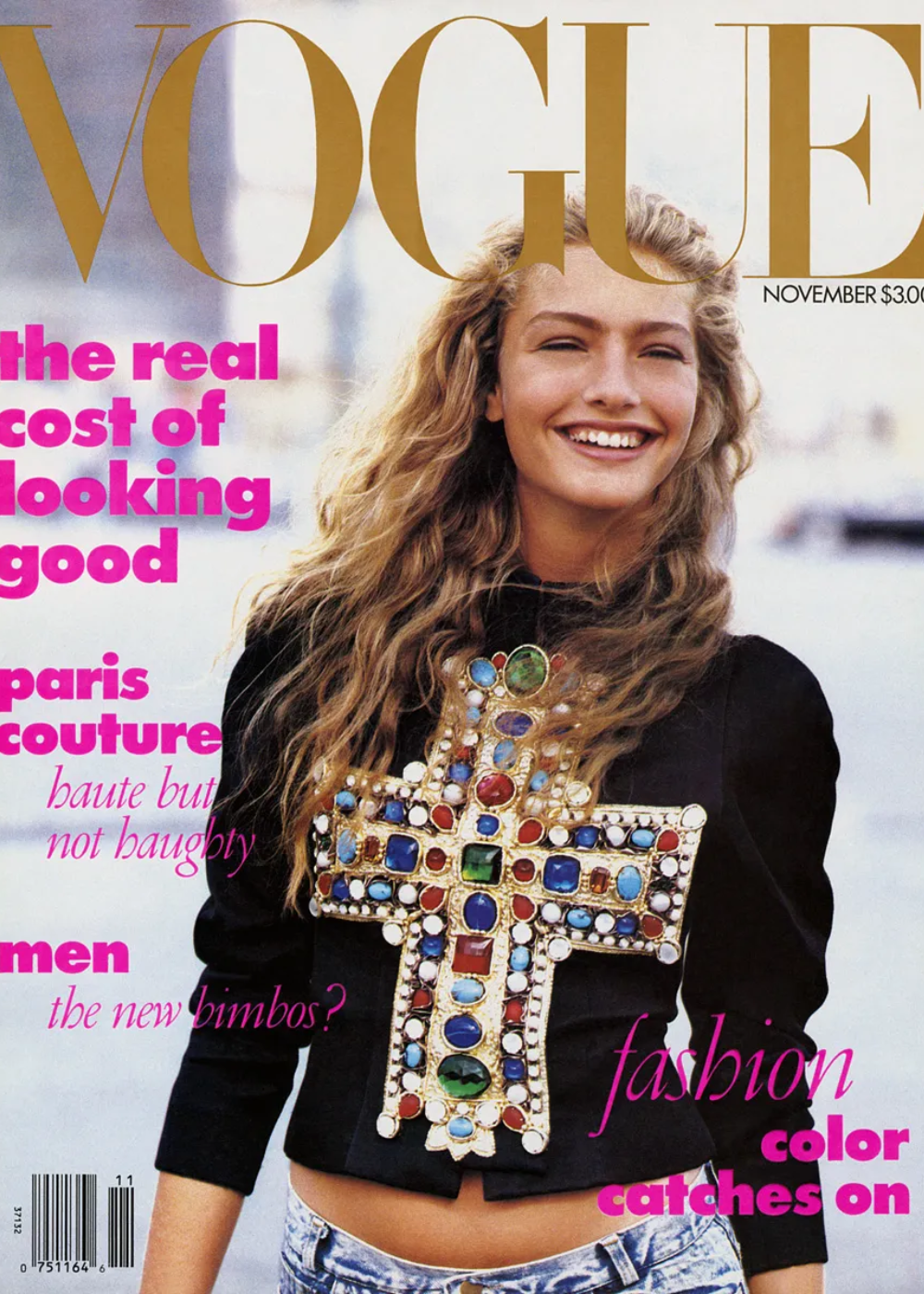Capa da revista Vogue com modelo sorridente, vestido com uma blusa de cruz ornamentada e jeans.