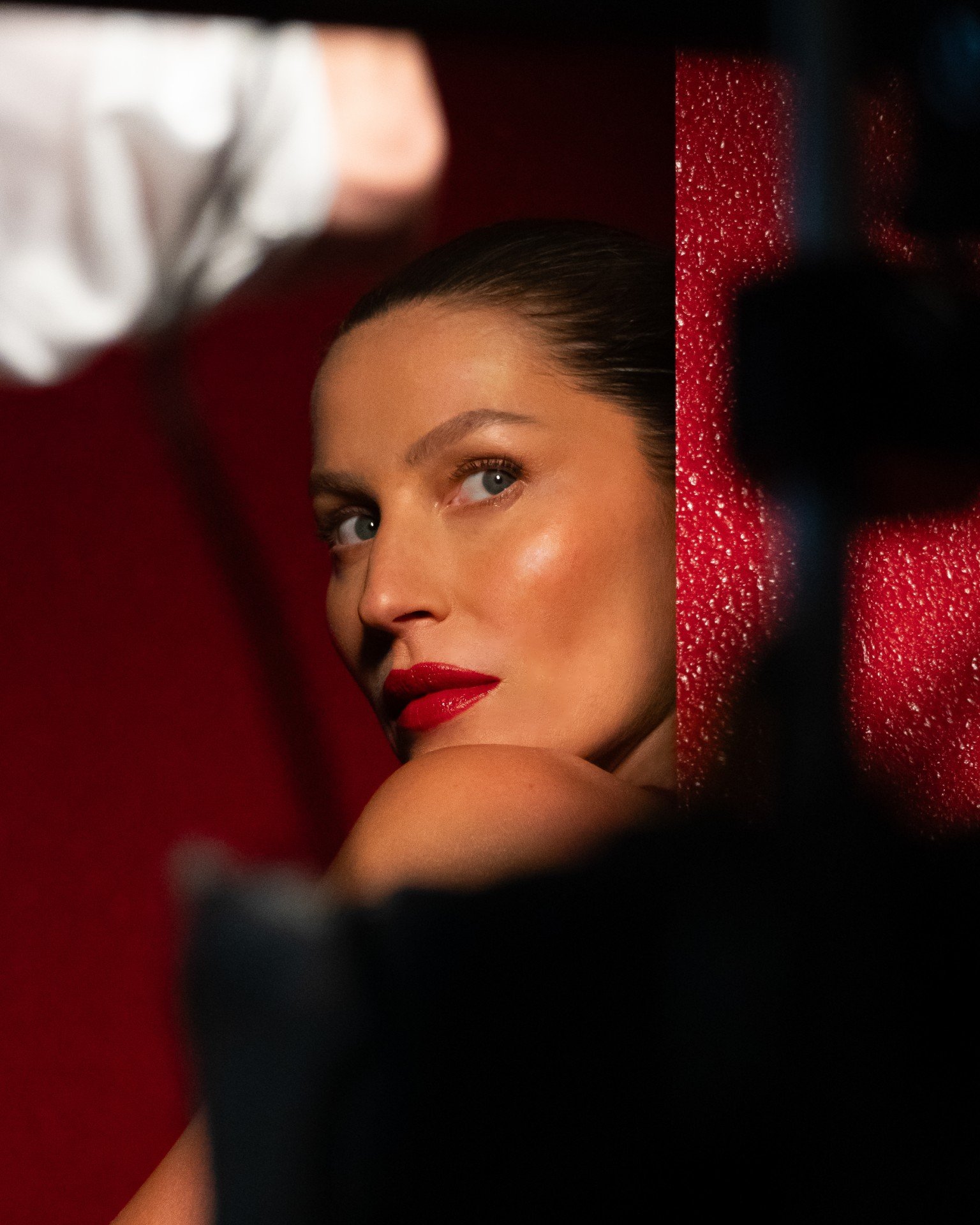 Não sei quem é a pessoa na imagem. Mulher com batom vermelho, olhando para o lado contra fundo vermelho.