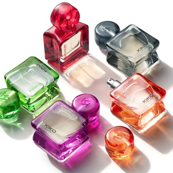 Frascos coloridos de perfumes KIKO Milano dispostos em uma superfície branca, refletindo luz.