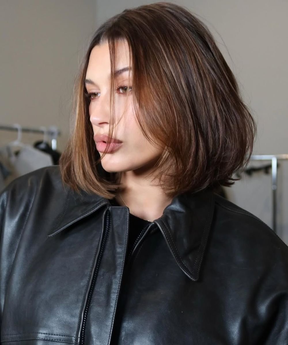 Mulher com cabelo curto e liso até os ombros, usando jaqueta de couro preta.