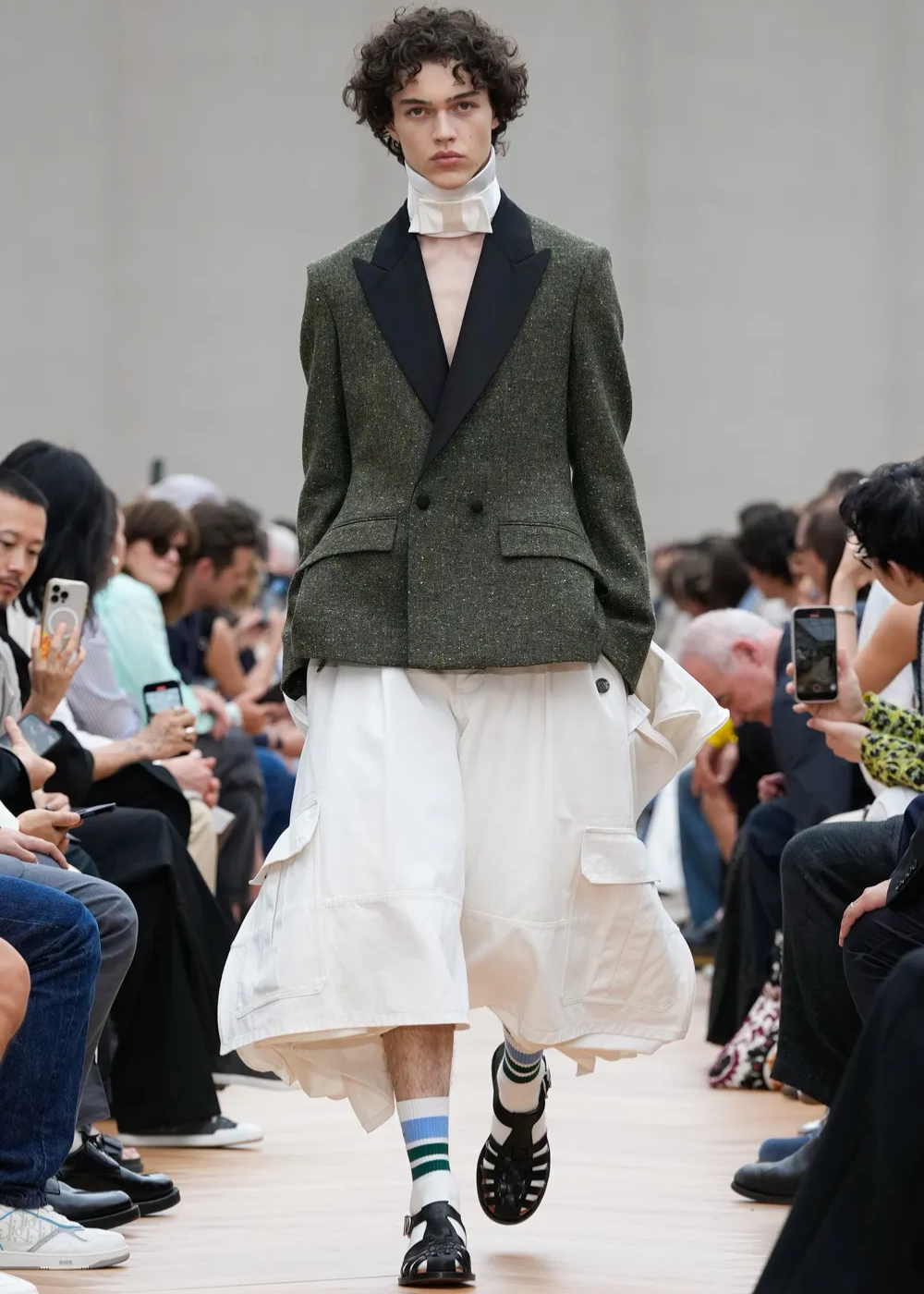 modelo usa blazer verde e calça branca, usando sandália no inverno.