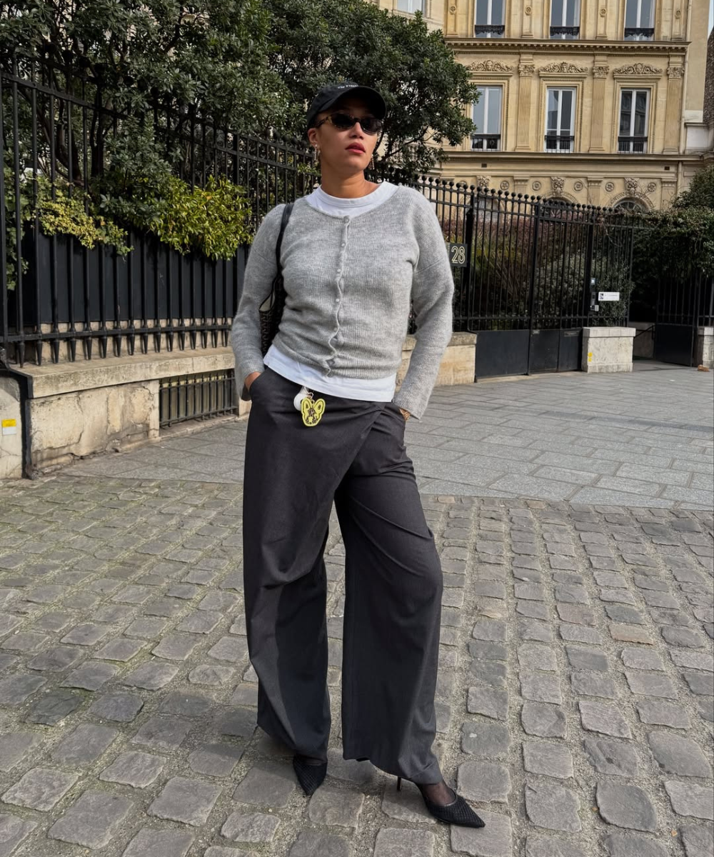 Pessoa usando suéter de tricô cinza e calça de alfaiataria preta, em um ambiente urbano.