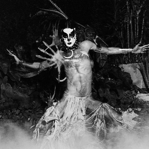 Ney Matogrosso, figura artística com adereços exóticos em ambiente noturno.