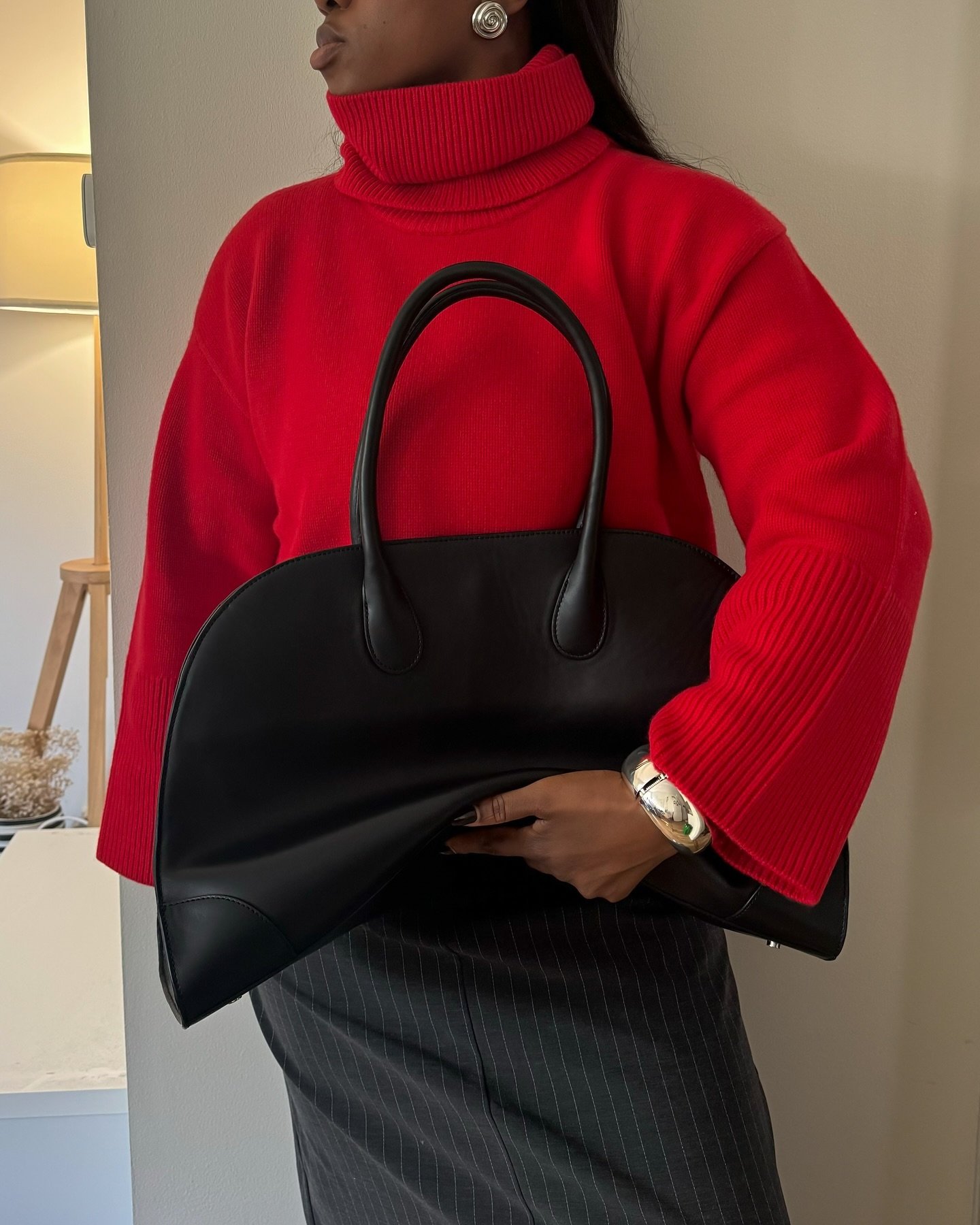 Suéter vermelho de gola alta com saia reta cinza e bolsa preta grande, ideal para looks de frio.