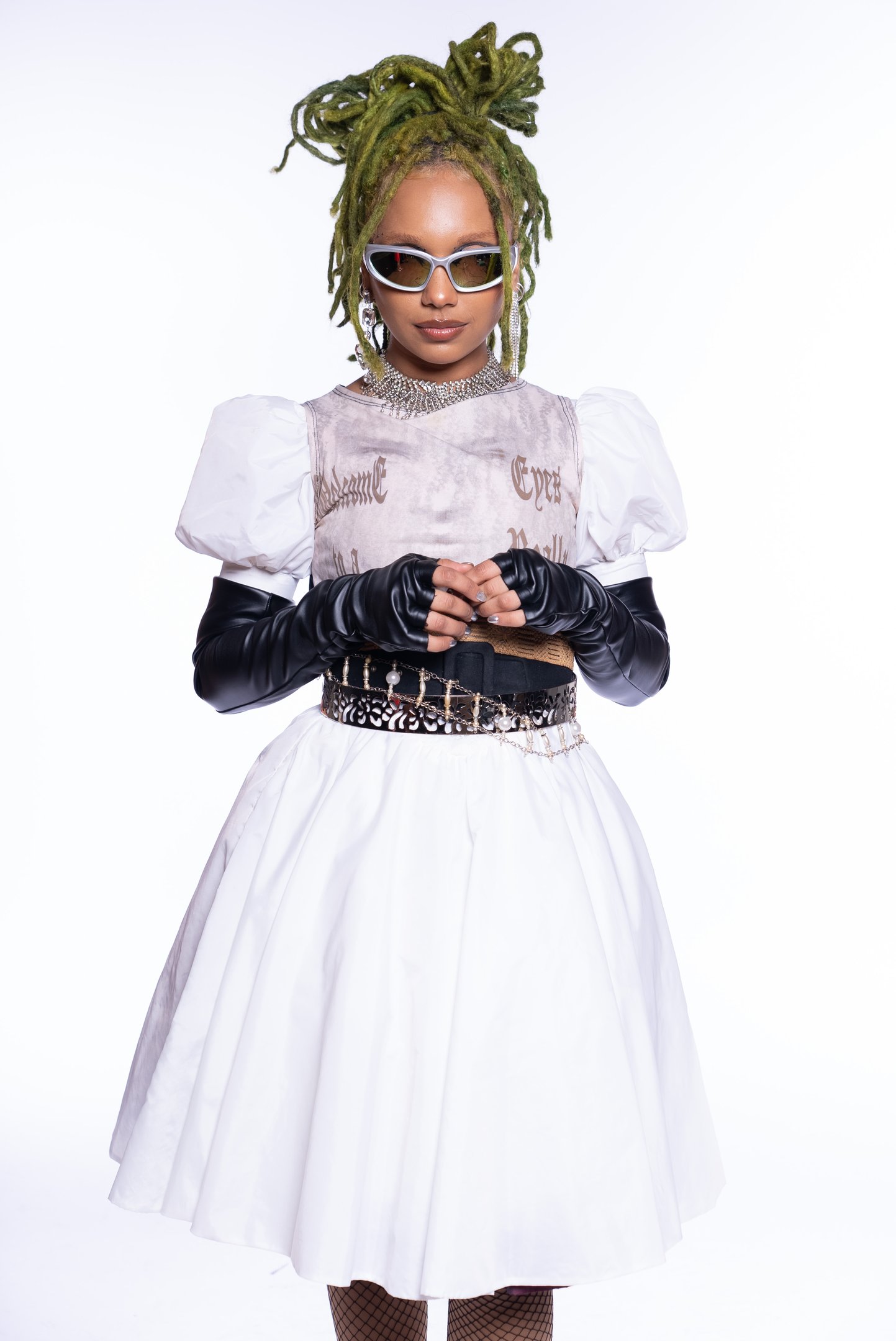 Nátaly Neri com tranças verdes, óculos de sol e vestido branco com mangas bufantes.