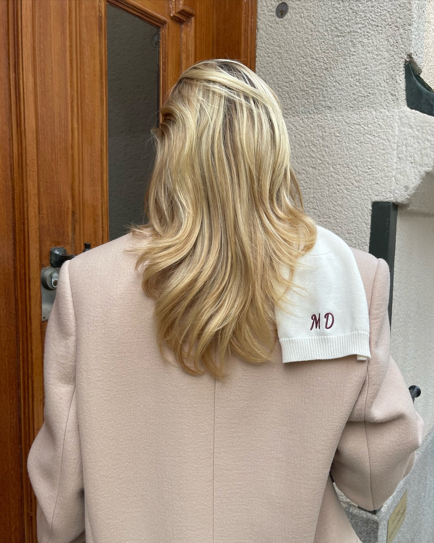 Loira de casaco bege, cabelos lisos e soltos. Detalhe do tecido bordado 