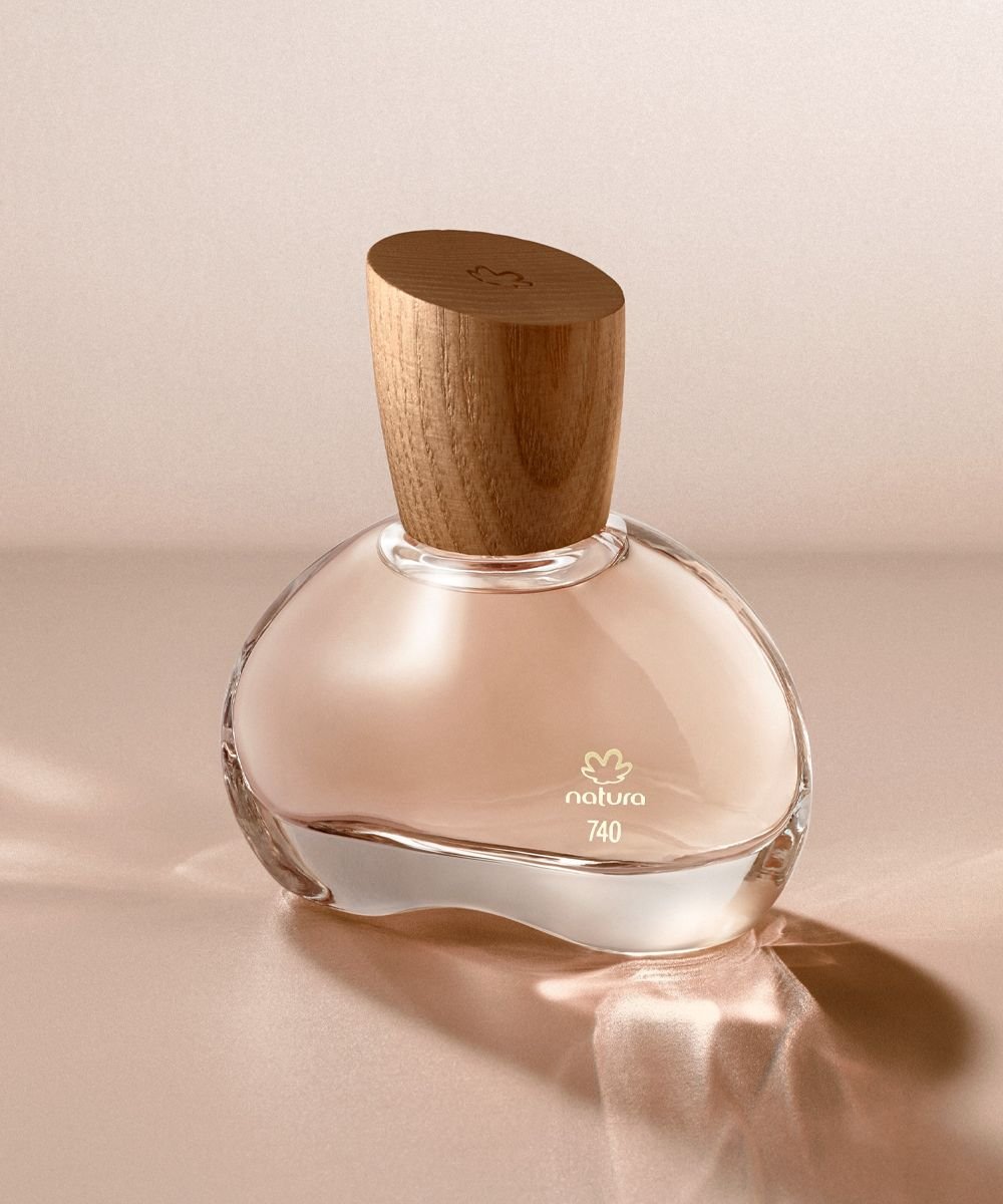 Frasco de perfume com tampa de madeira, refletindo na superfície. Marca conhecida de perfumes nacionais.