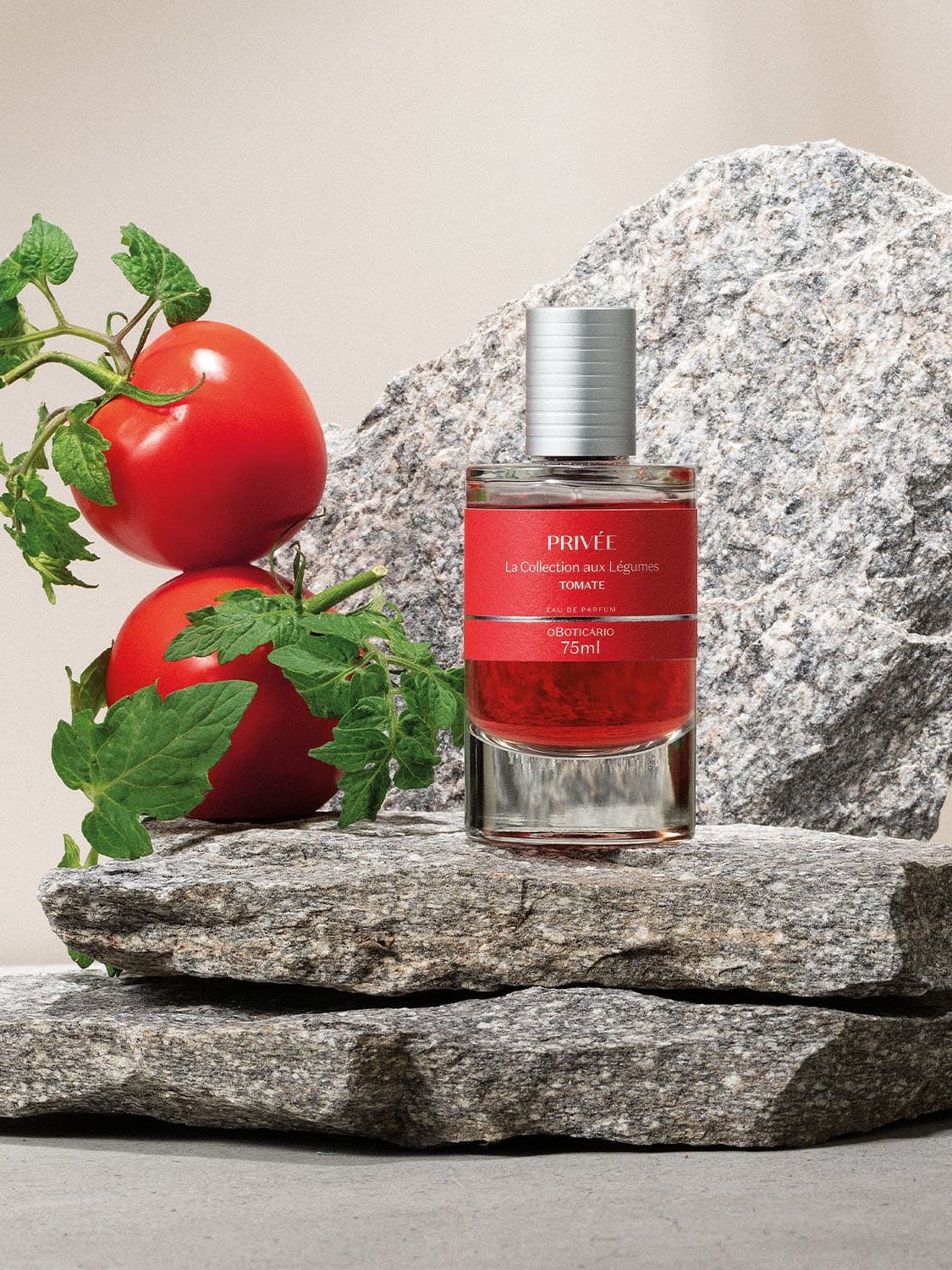 Frasco de perfume entre tomates frescos sobre pedras, simbolizando perfumaria comestível.