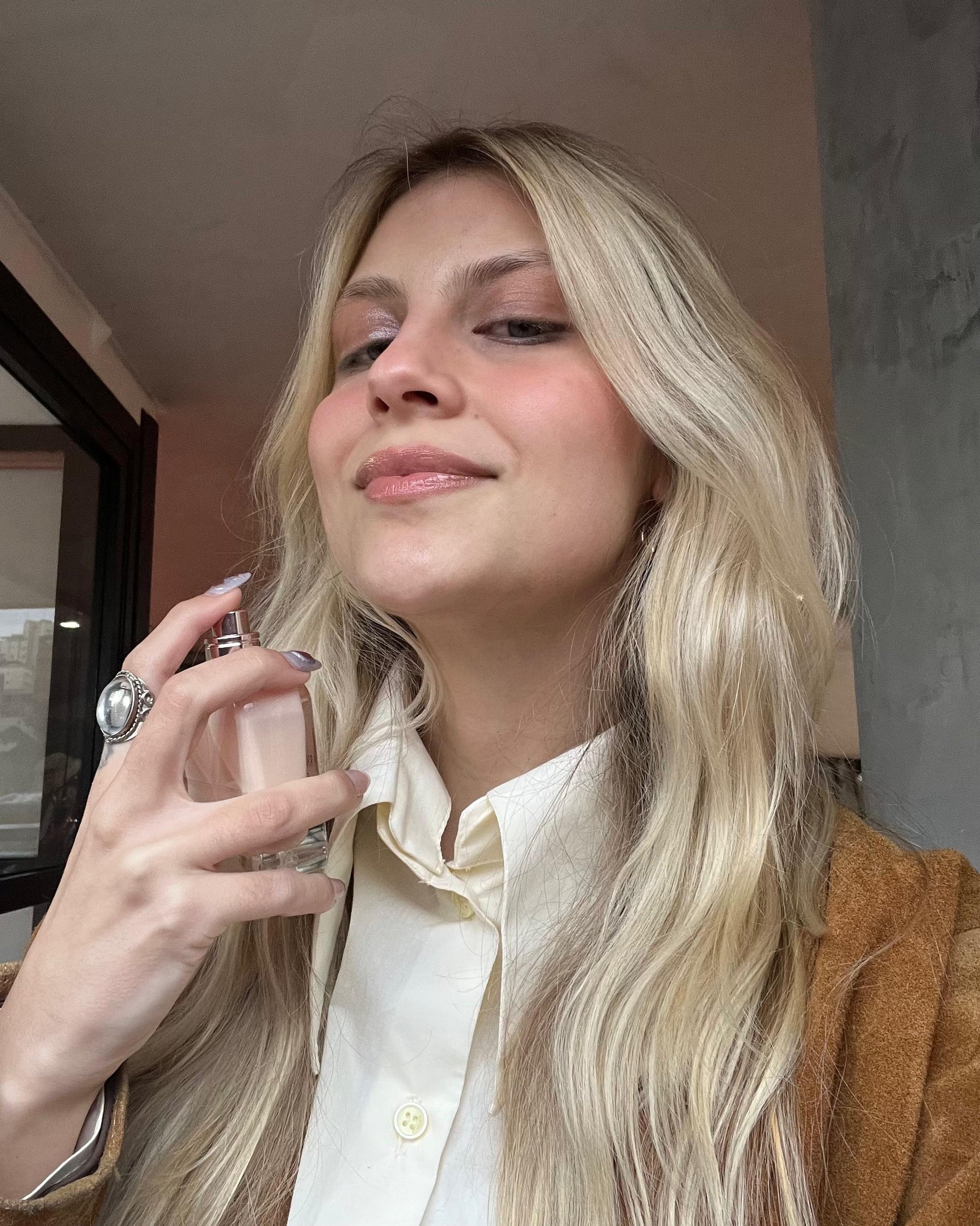 Mulher loira usando fragrância, evocando sensação de perfume de inverno.