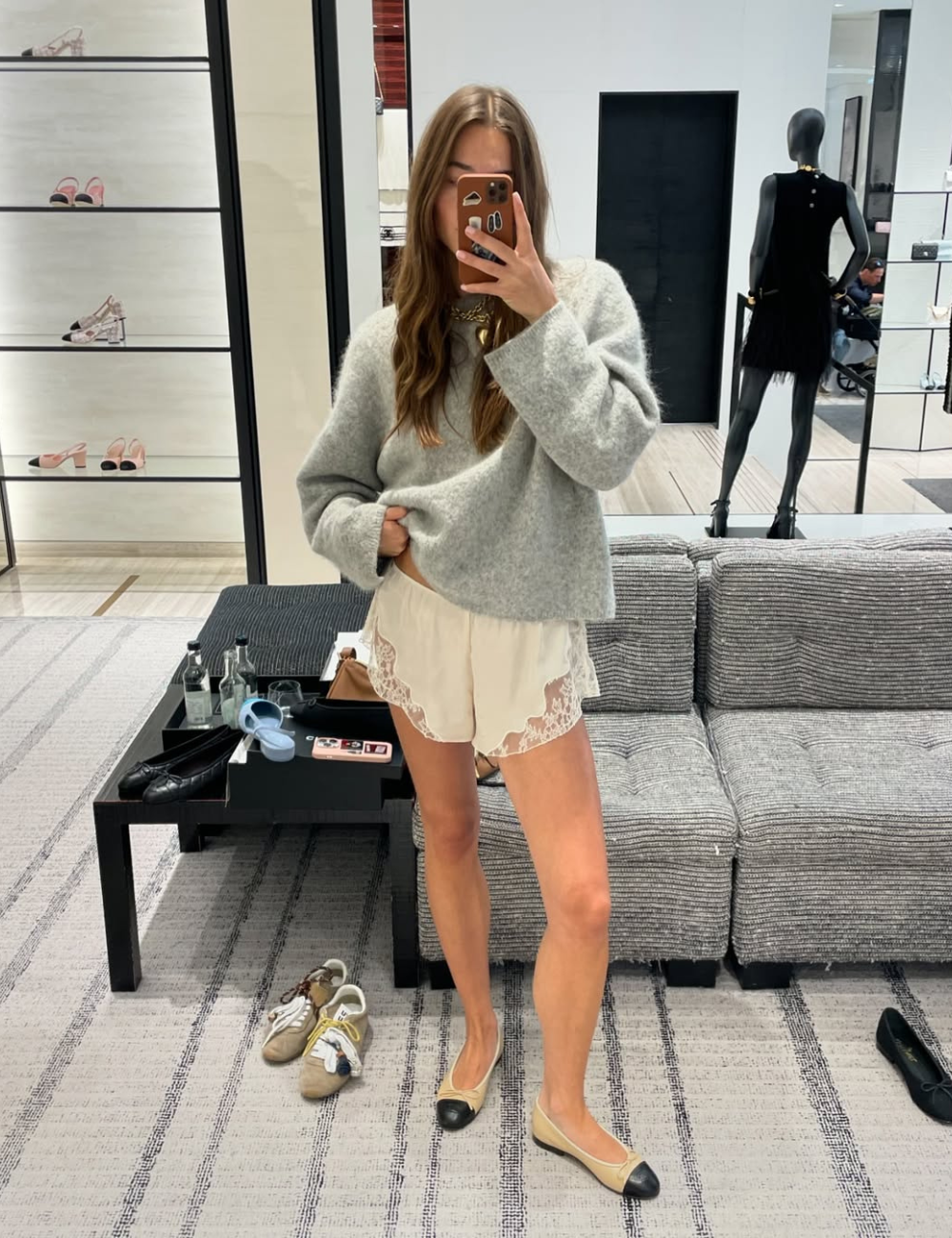 Pijama é tendência no look. Pessoa em loja tirando selfie no espelho com short de cetim e renda.