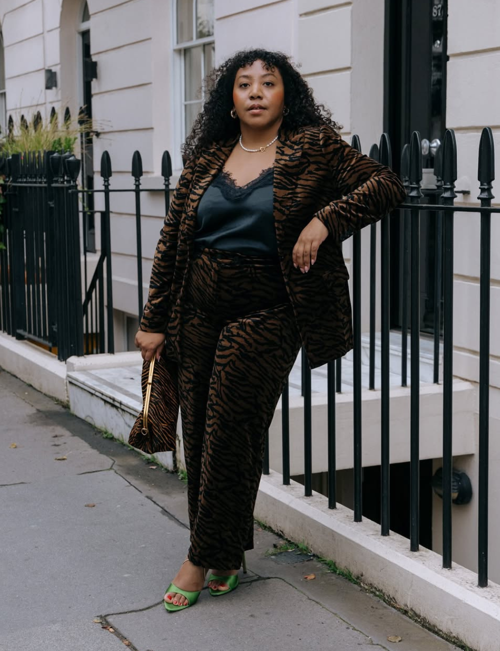 Mulher com conjunto estampado animal print, semelhante a um pijama, posa confiante na rua.