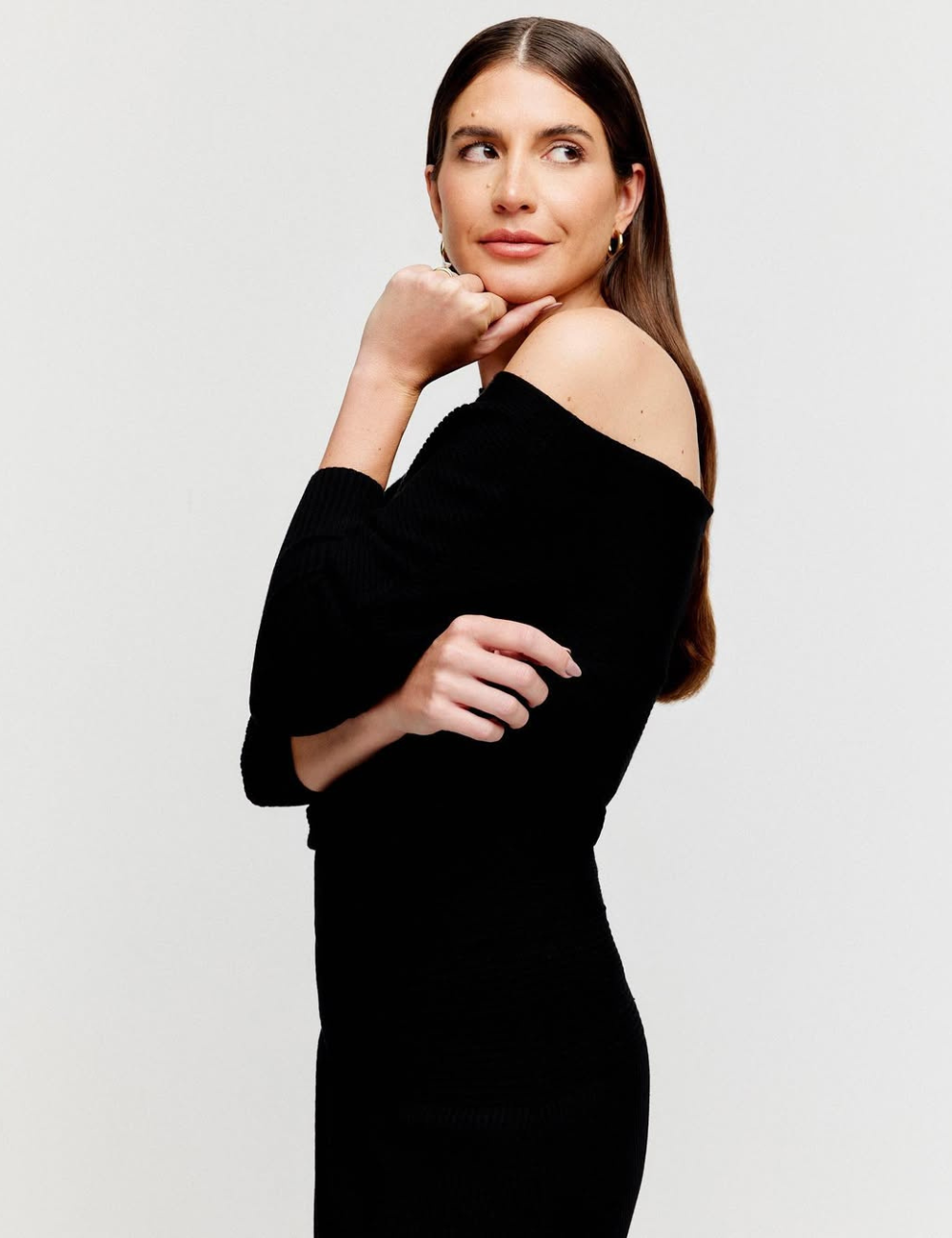 Mulher em vestido preto ombro a ombro, símbolo de Power Dressing, com expressão confiante e olhar de lado.