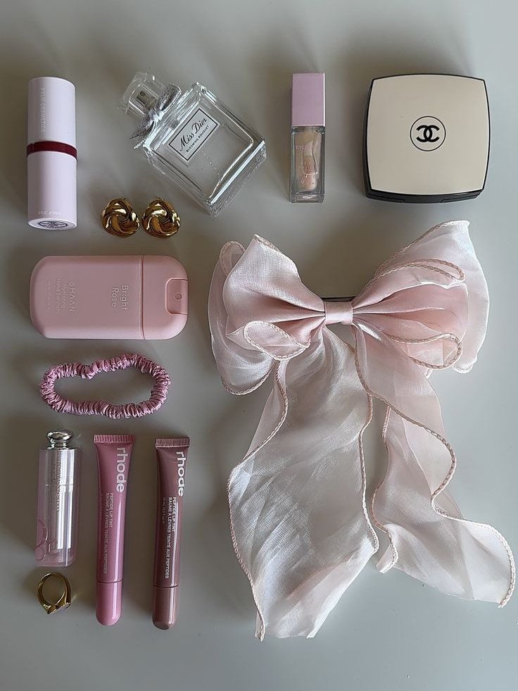 Itens de beleza em tons de rosa, incluindo perfumes, batons, grampo e laço. puberdade precoce