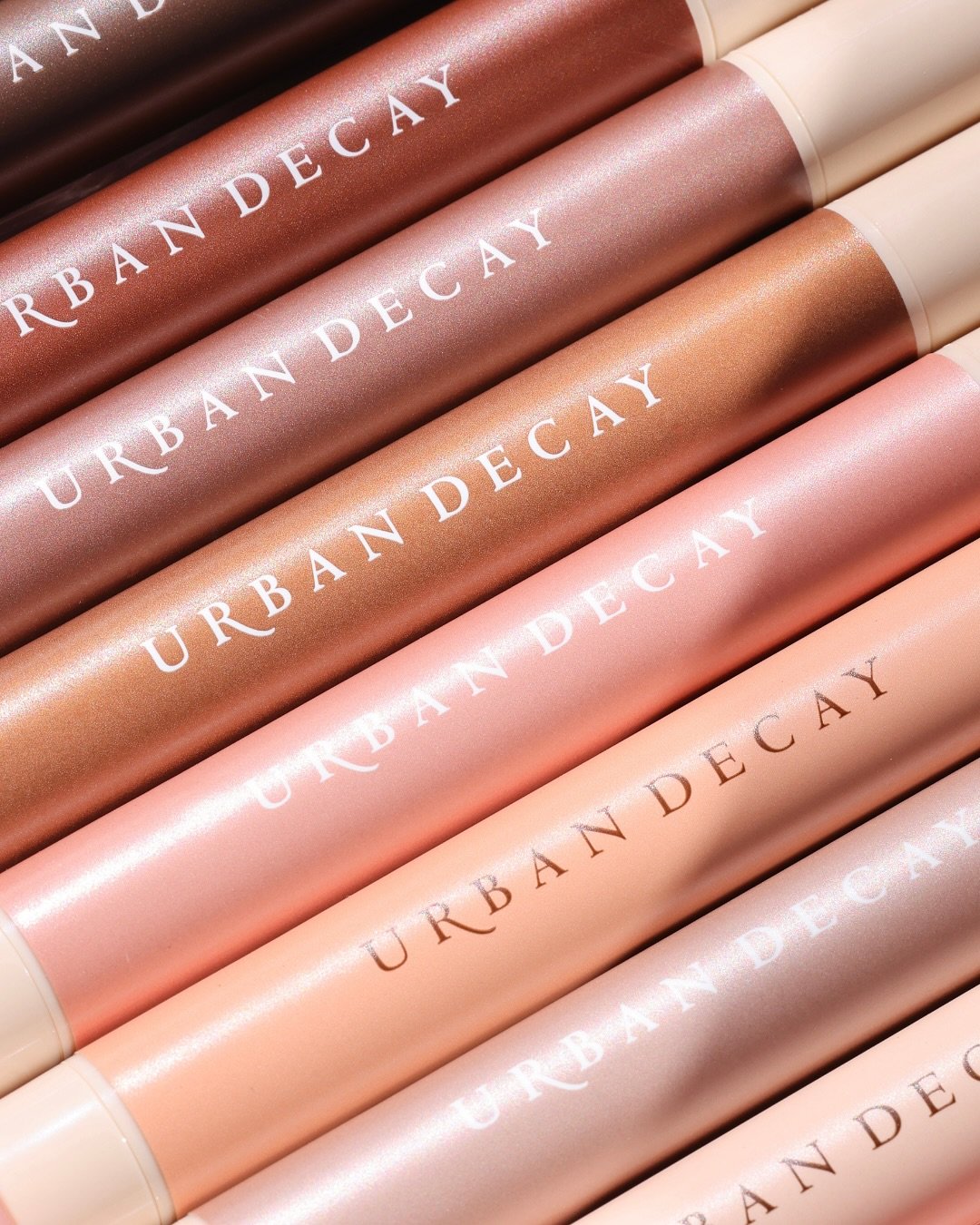 Tubos de maquiagem em tons rosa e marrom com marca Urban Decay.