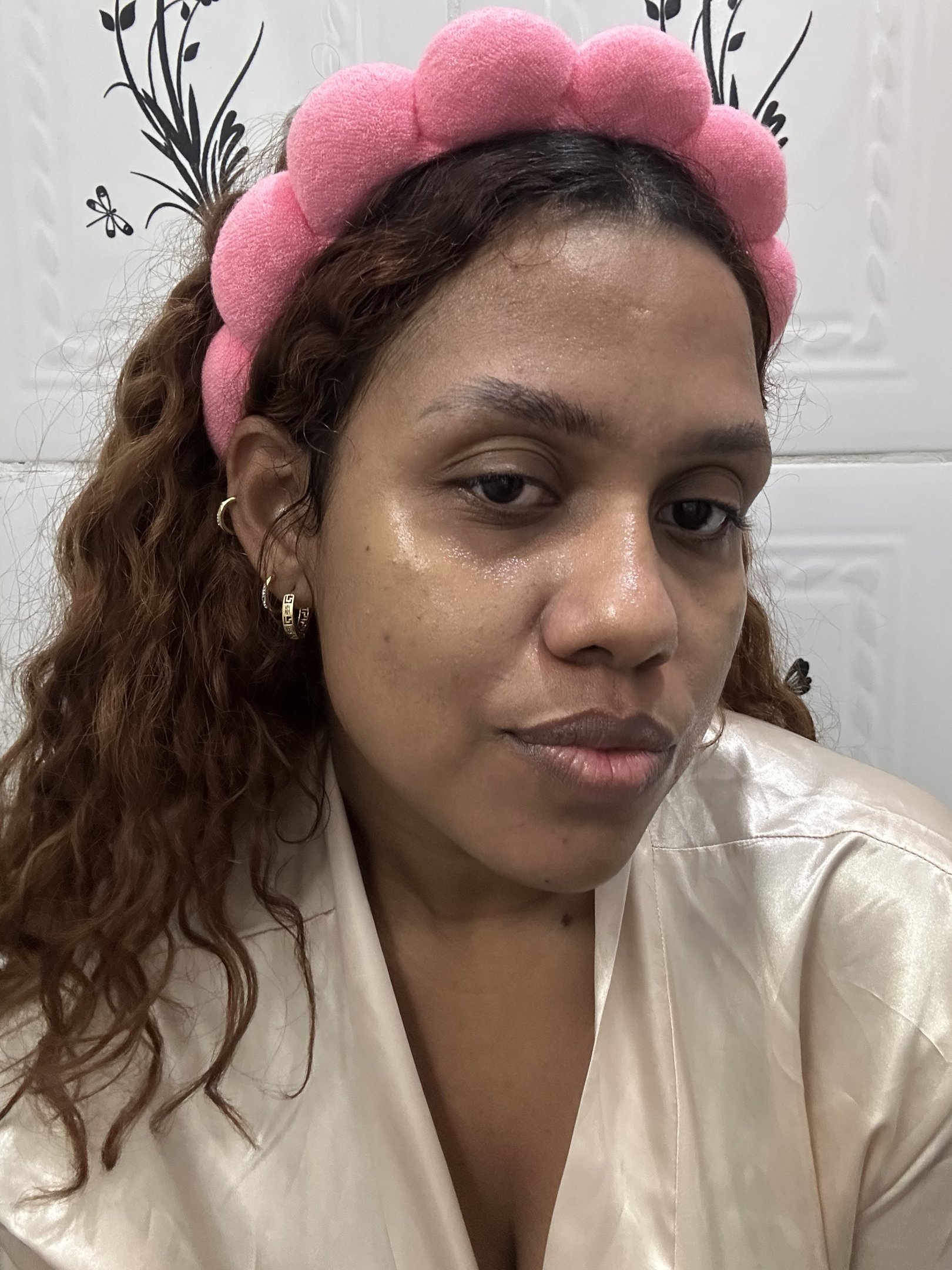 máscara argila. Mulher usando tiara rosa com fundo decorativo.