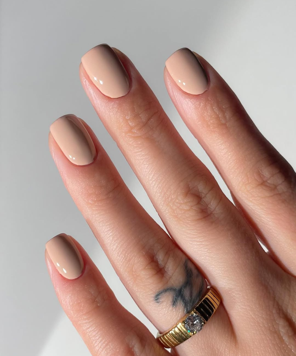 Unhas em tom nude, exemplo de cores de unha para noivas, com anel dourado no dedo anelar.