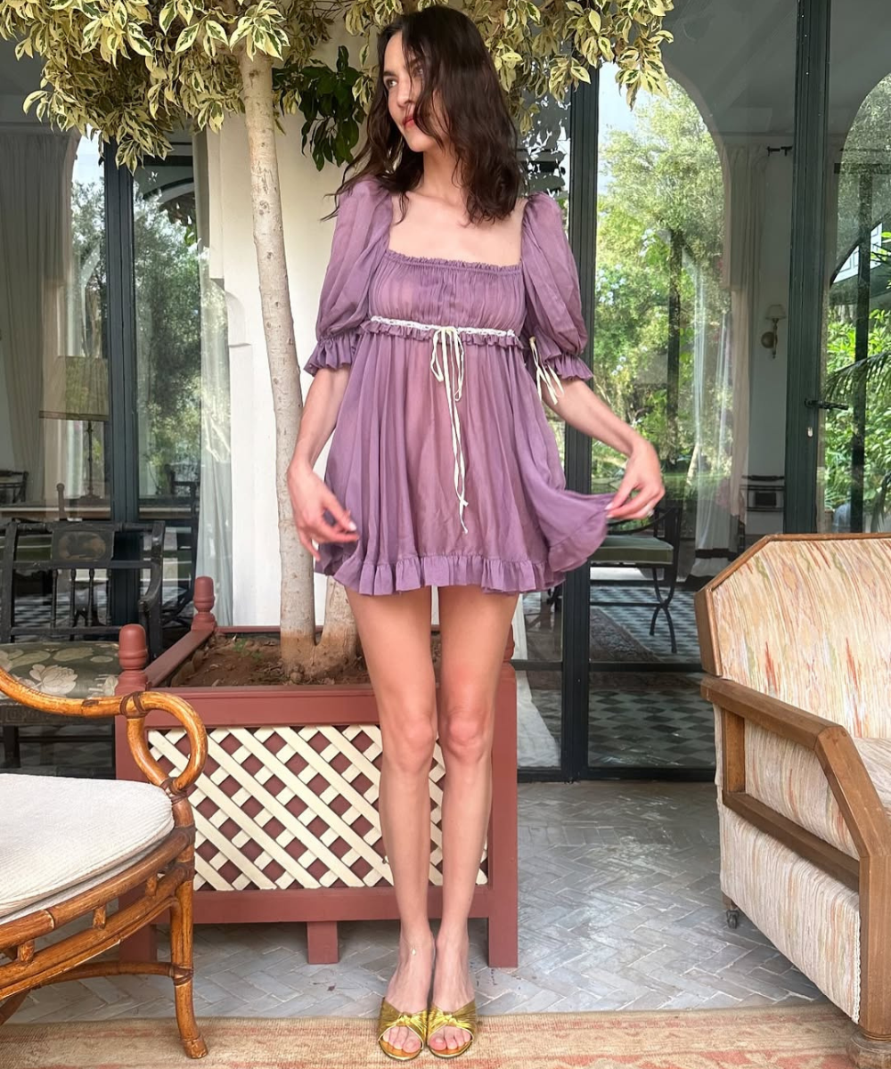 Vestido lilás curto com mangas bufantes usado em ambiente interno elegante.