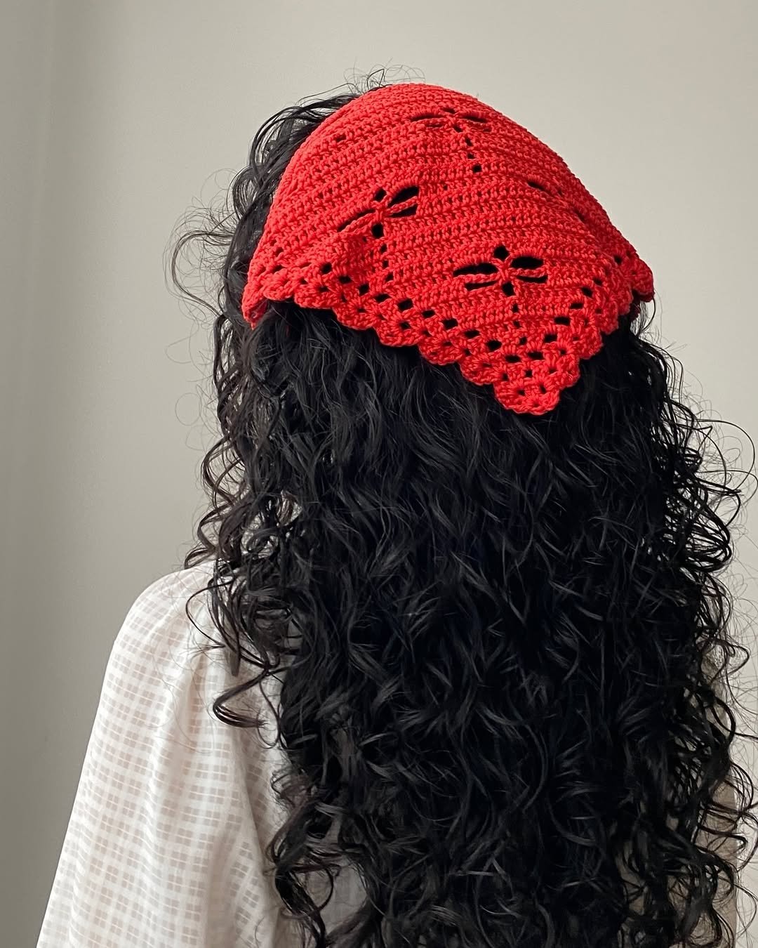 Cabelo cacheado com bandana de crochê vermelha, destacando o padrão detalhado.