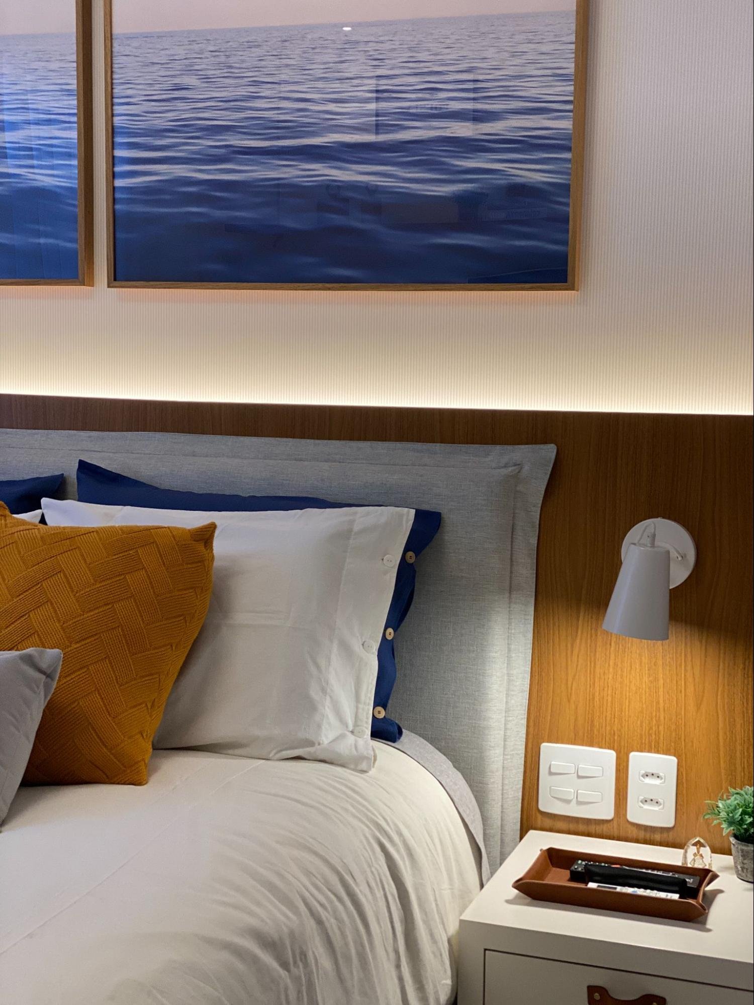 Quarto acolhedor com cama, travesseiros coloridos e cabeceira iluminada, parte de uma casa aconchegante.