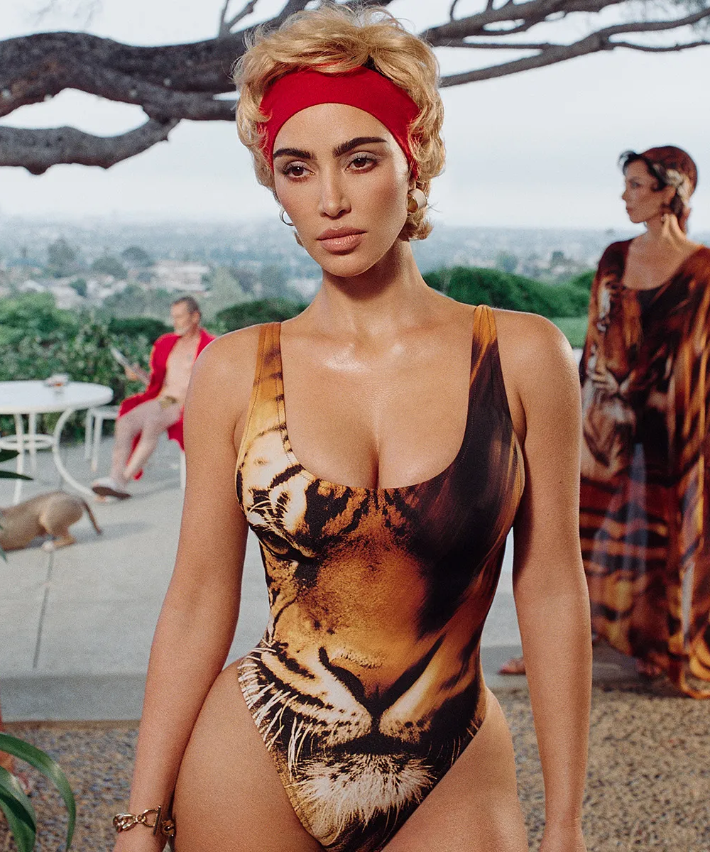 Pessoa com maiô estampado de tigre e faixa vermelha na cabeça em cenário ao ar livre. Collabs de moda elegante.