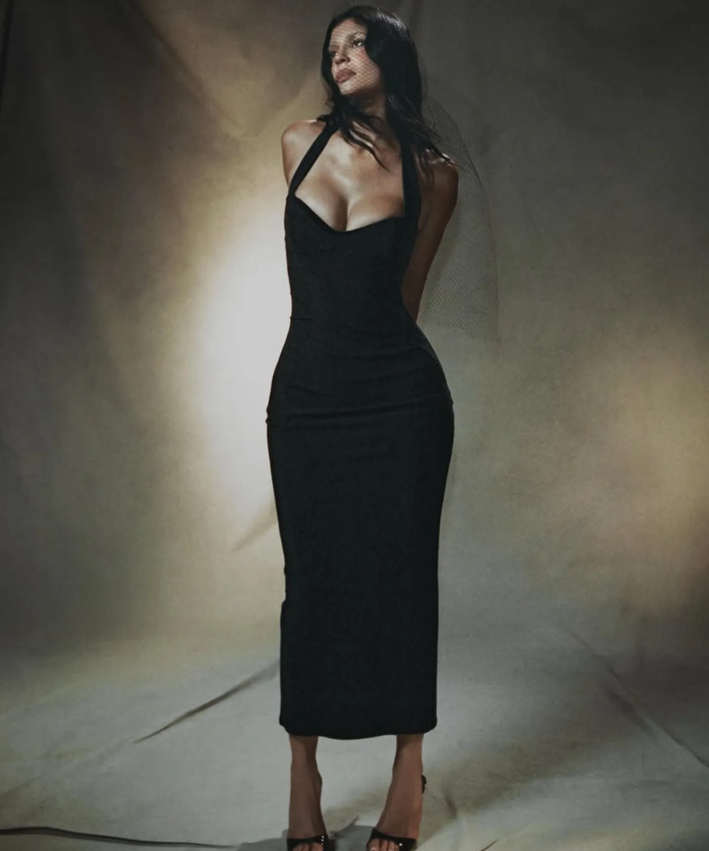 Modelo em vestido preto elegante, simbolizando colaborações na moda.