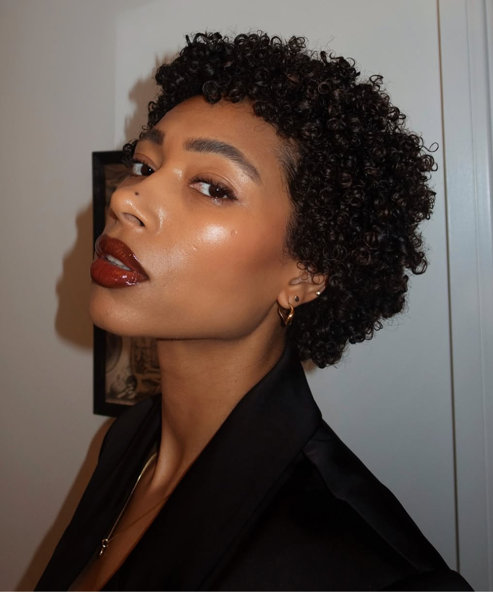 Pessoa com cabelo cacheado curto, representando a transição capilar e estilo natural. O big chop é uma forma de como acelerar a transição capilar.