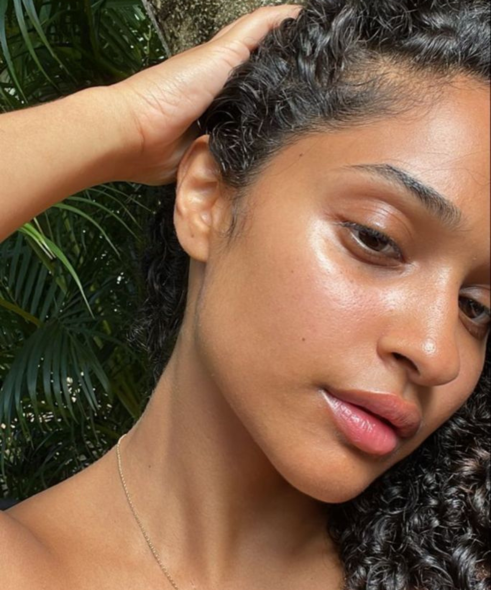 A pele saudável de uma mulher sob o sol, destacando cuidados para evitar espinhas.