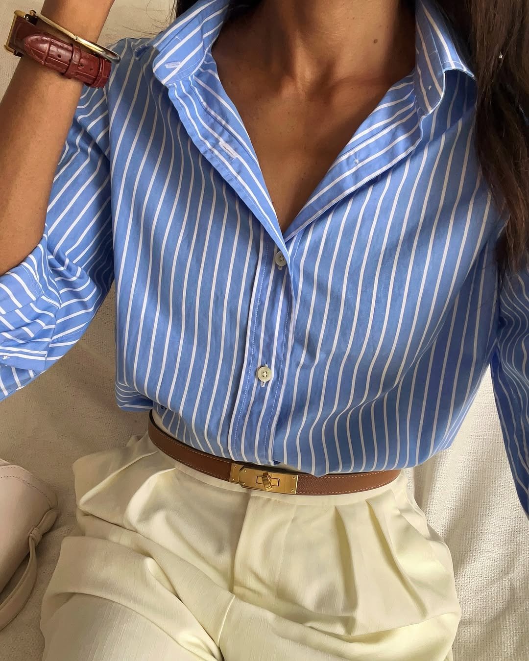 Blusa listrada azul com calça bege e cinto marrom, ideal para entrevista de emprego.