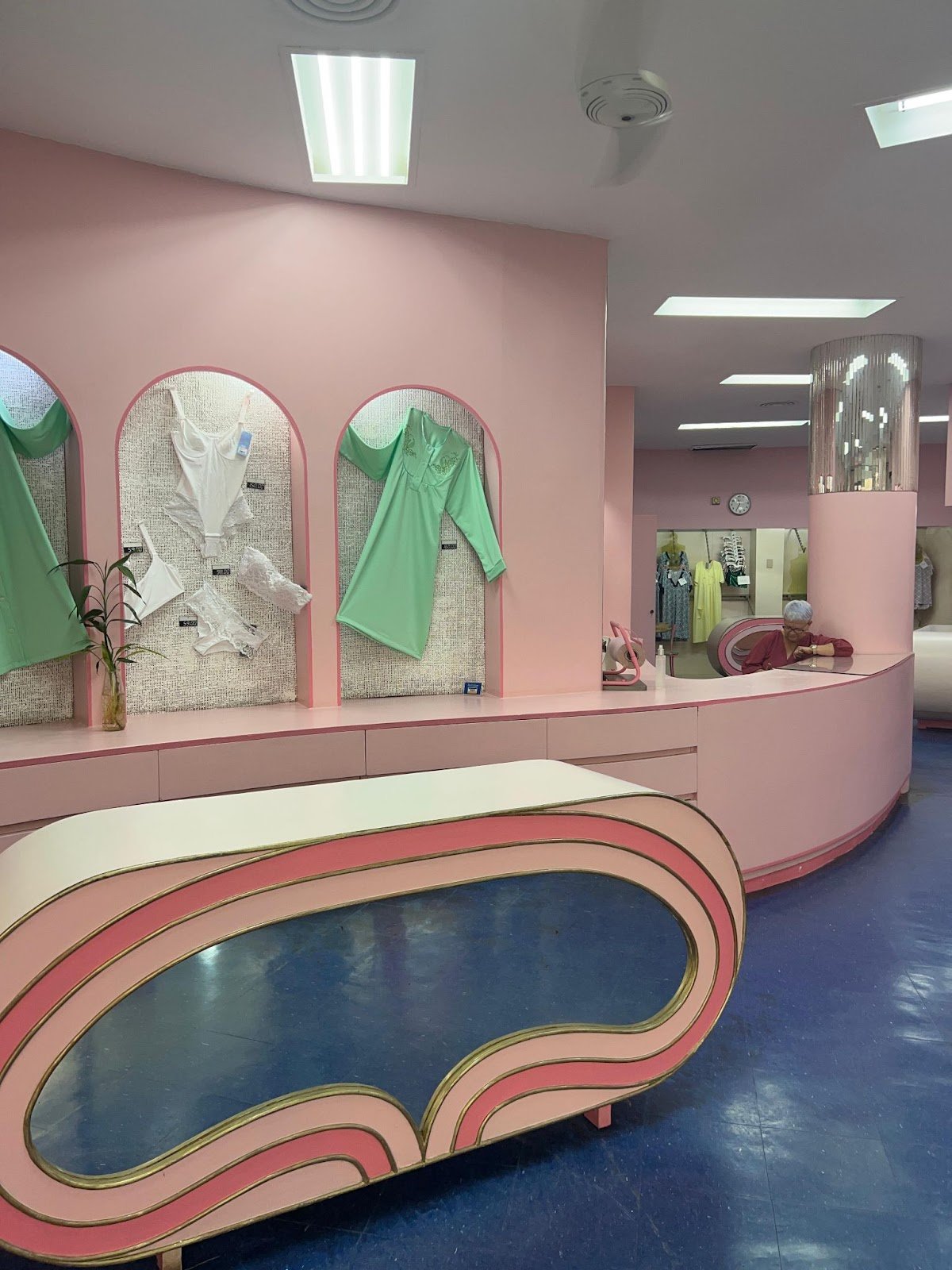 Sala com parede rosa e roupas expostas, fundo retrô, estilo em Copacabana.