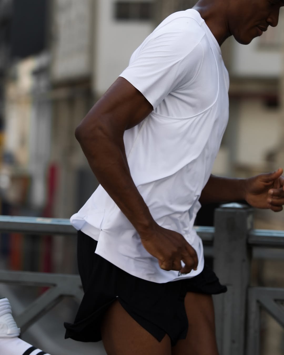 Corredor de camisa branca e shorts pretos em uma rua urbana, simbolizando a cultura da corrida.