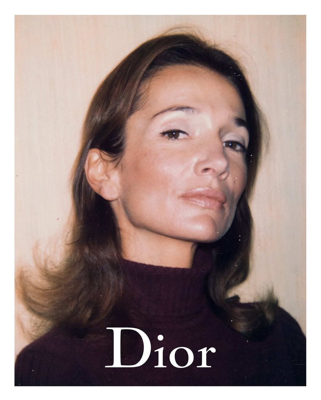 Lee Radziwill com suéter roxo, olhar confiante, fundo liso, com a palavra 