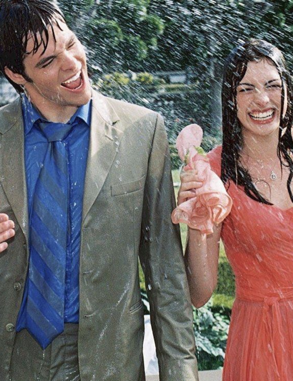 Dois jovens rindo sob água, em uma cena alegre que lembra momentos de comédias românticas.