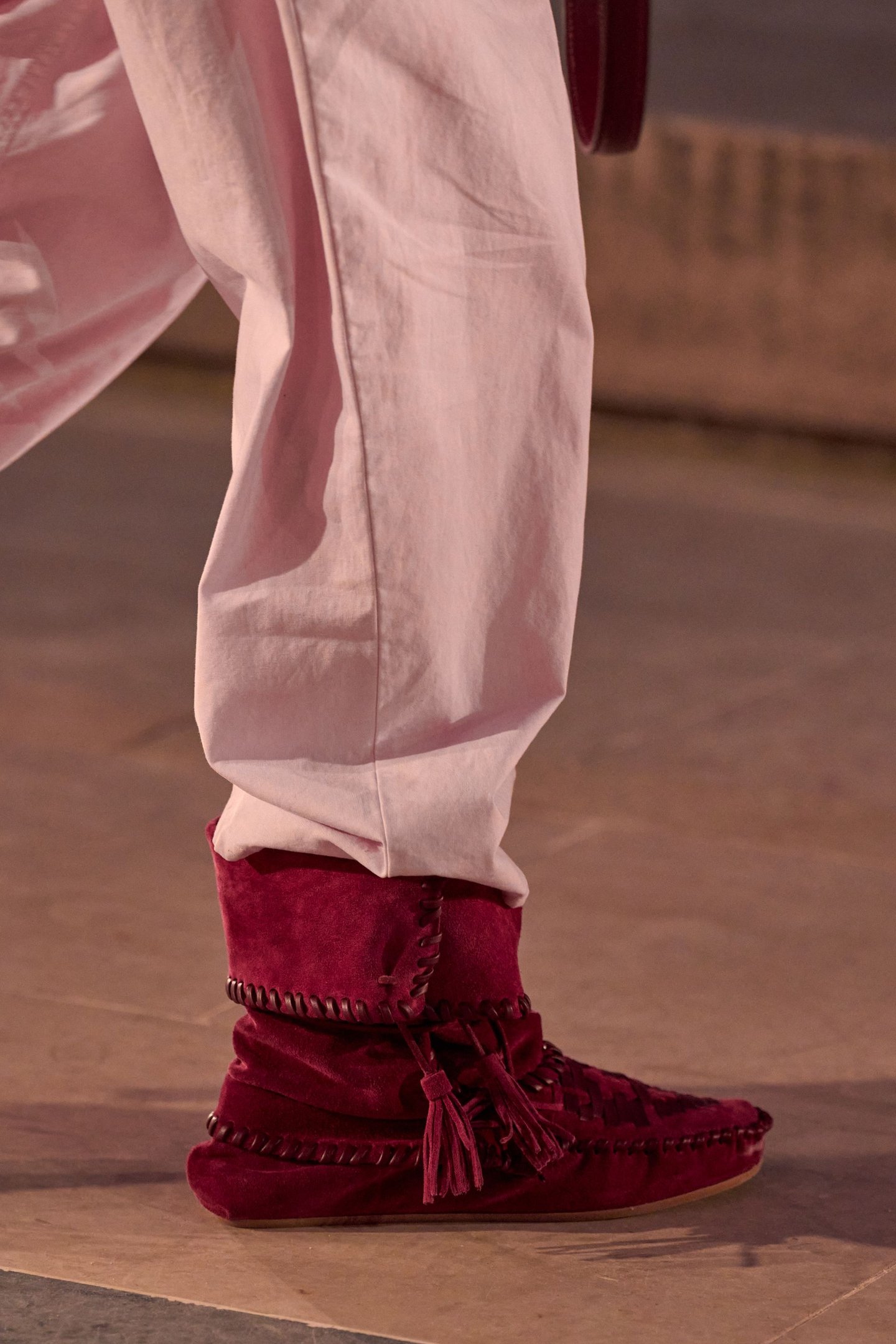 Calça rosa clara sobre bota vermelha de veludo, cano franzido com cadarço decorativo.
