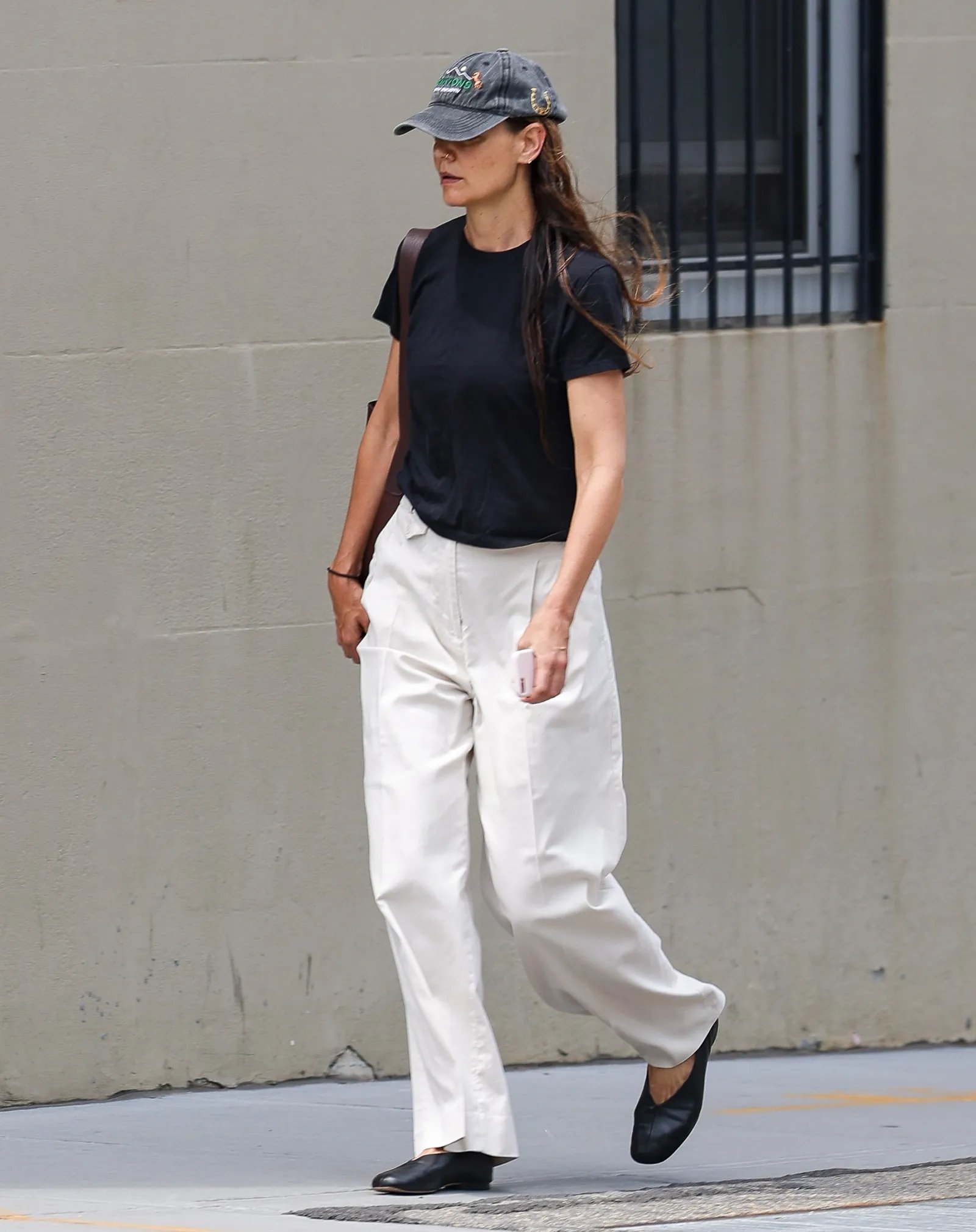 Pessoa usa calça branca e camiseta preta, combinando com sapato elegante e confortável, caminhando ao ar livre.