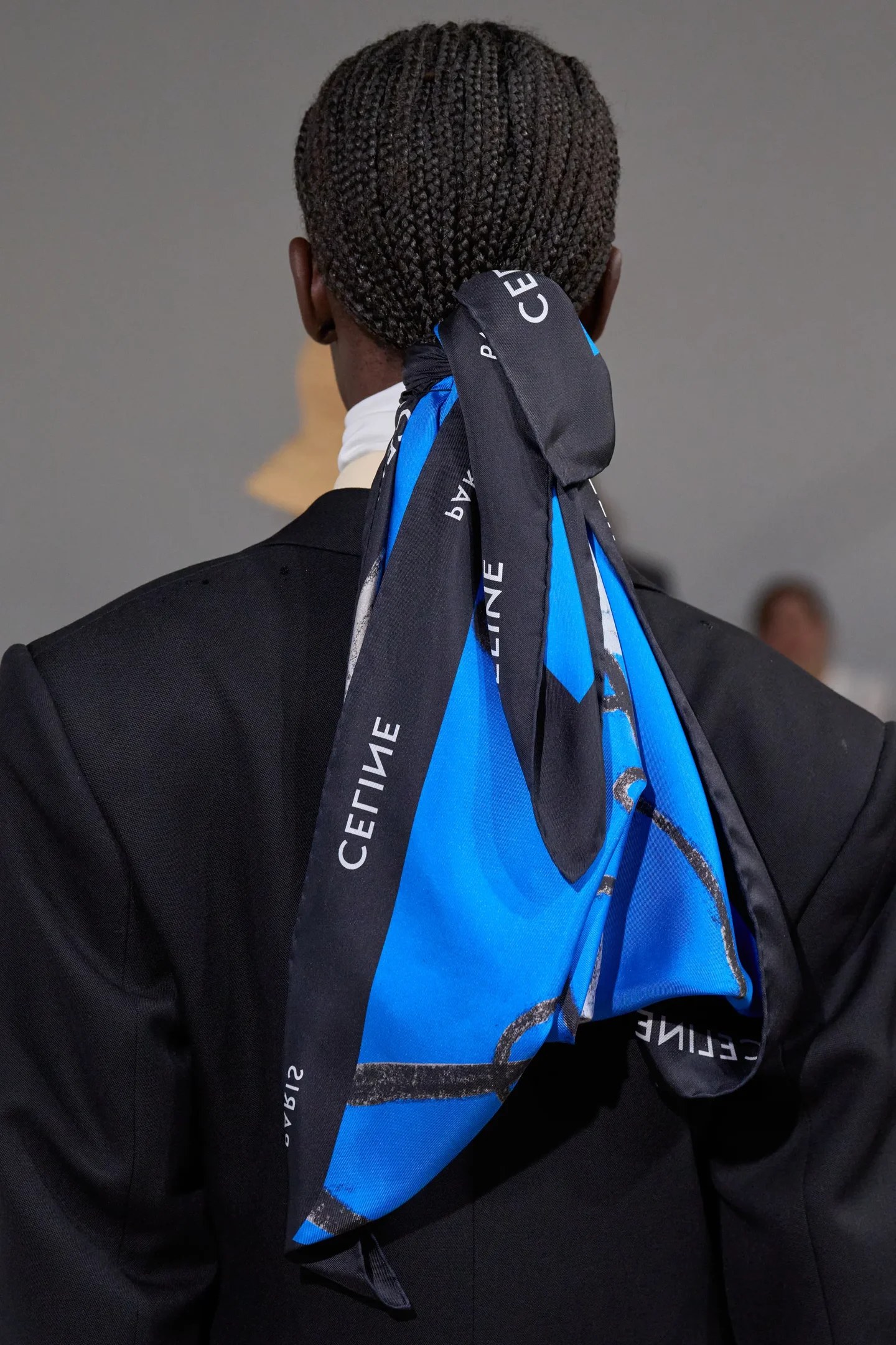 Tranças presas por um lenço azul e preto com logotipo.