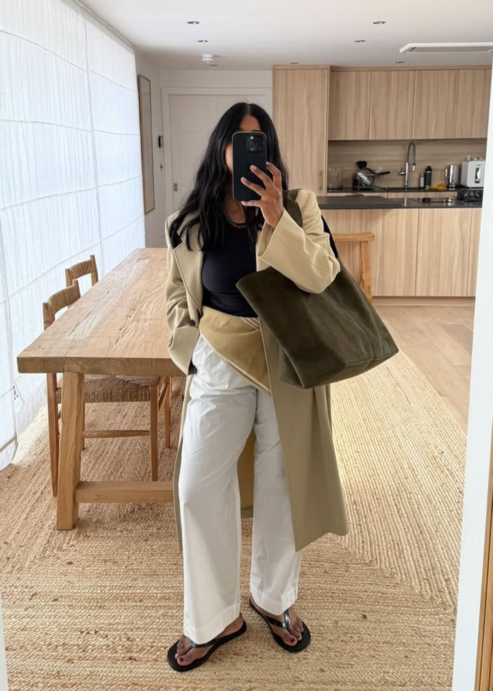 Descrições de moda casual não mostram um lenço no quadril. Sugestão alternativa: Mulher com casaco bege, camiseta preta e calça branca.