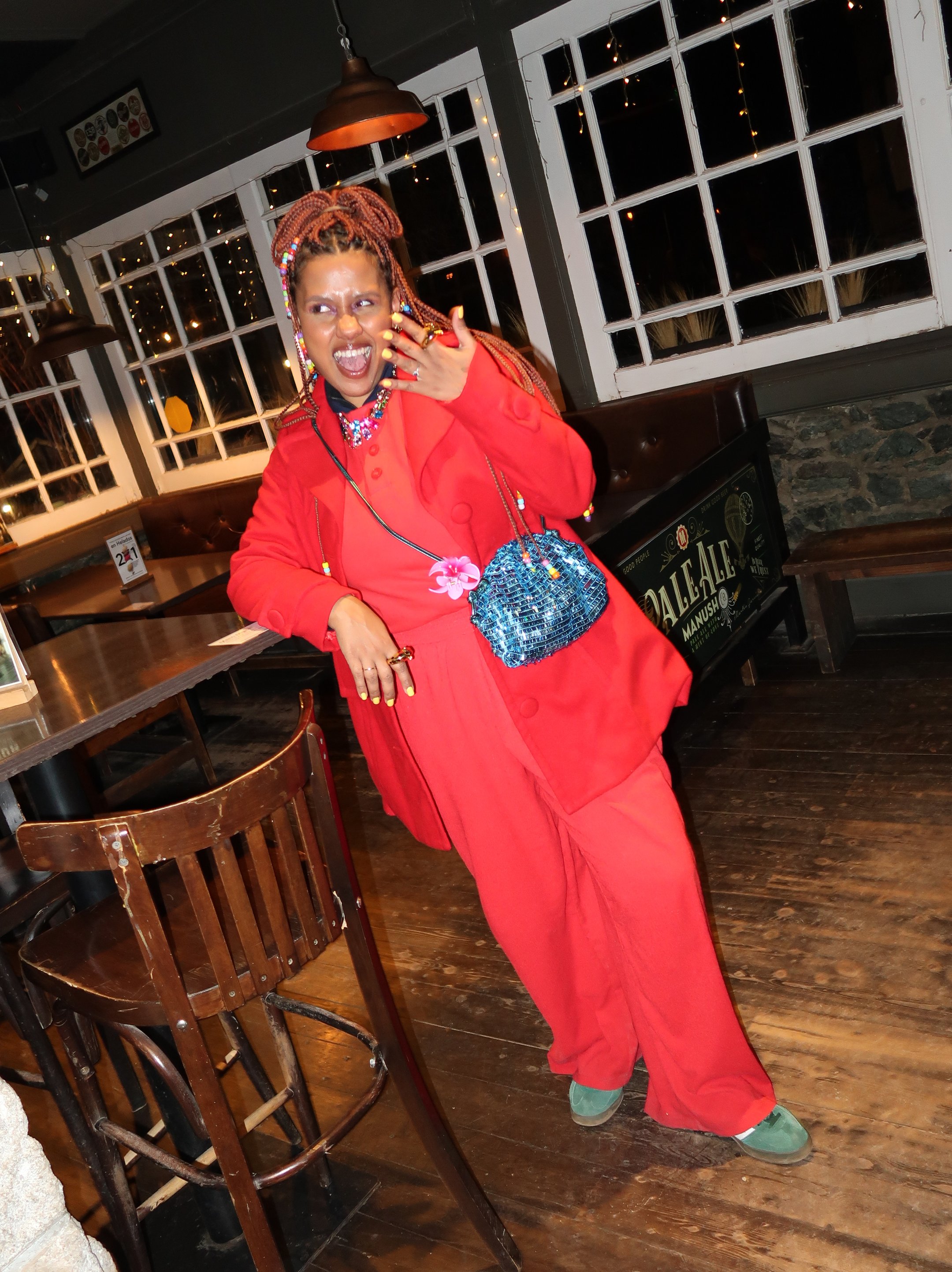 Pessoa com casaco vermelho vibrante, bolsa azul brilhante, exibindo estilo em looks de inverno coloridos.