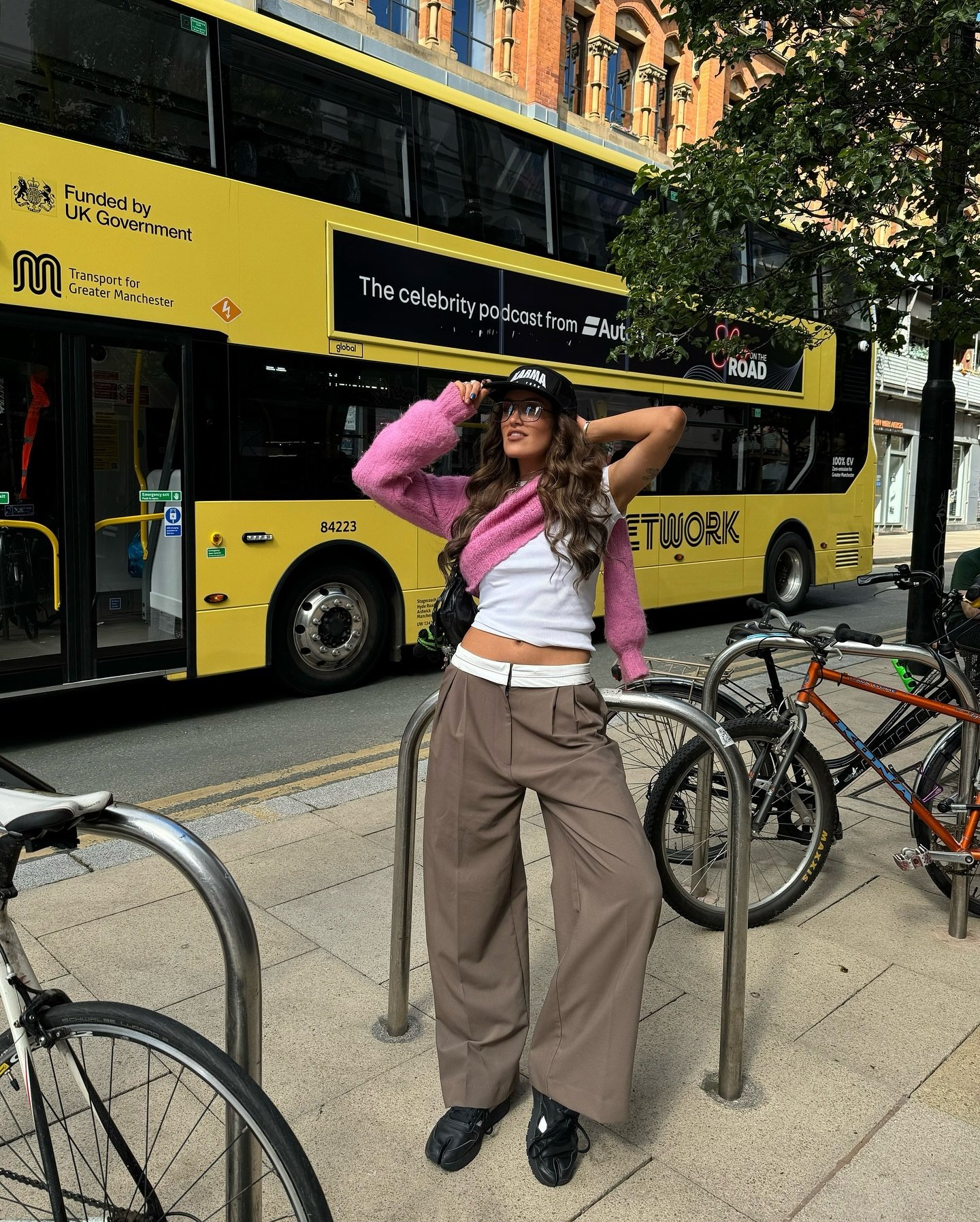 Pessoa com roupa casual e óculos de sol posa em frente a um ônibus amarelo. Calçado Nike Air Rift preto.