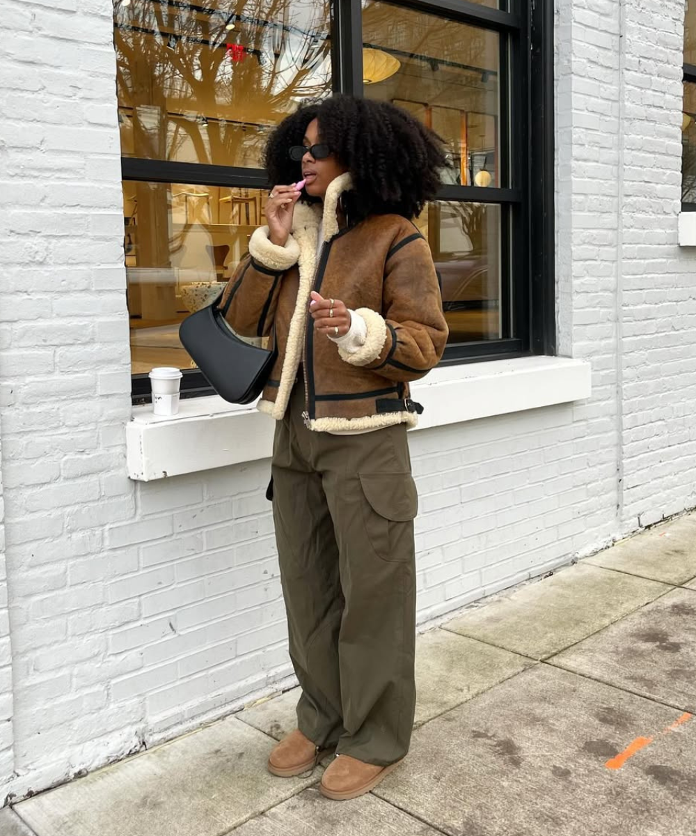 Pessoa tomando café vestindo casaco forrado e sapatos combinando em frente a uma vitrine.