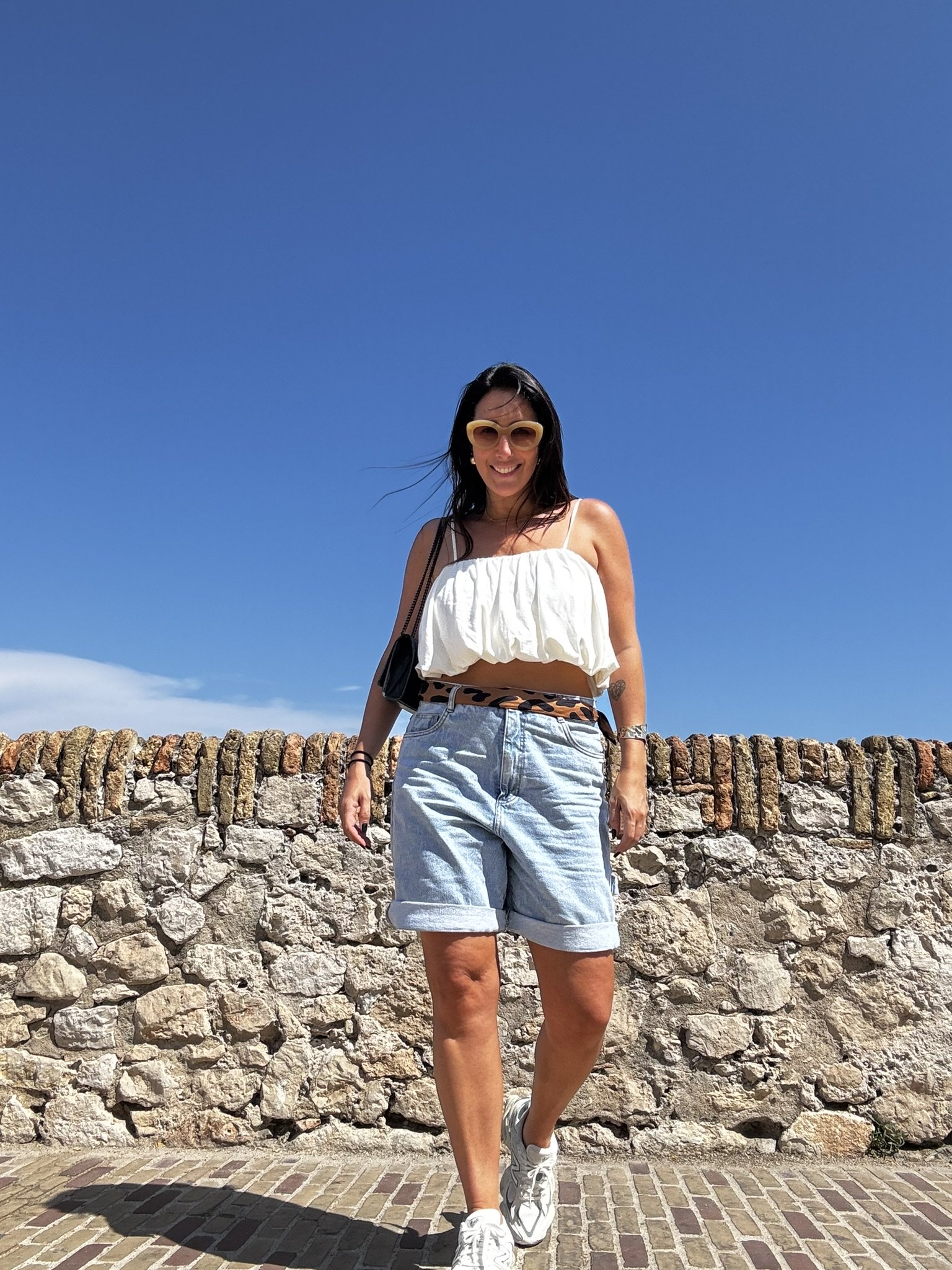Mulher caminhando em um dia ensolarado com céu azul, representando o clima do verão europeu.