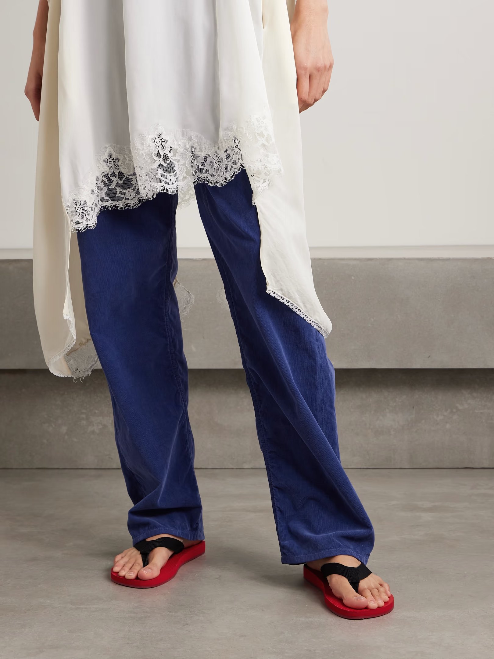 Calça azul e túnica branca rendada com chinelos modernos vermelhos e pretos. Sapatos do momento