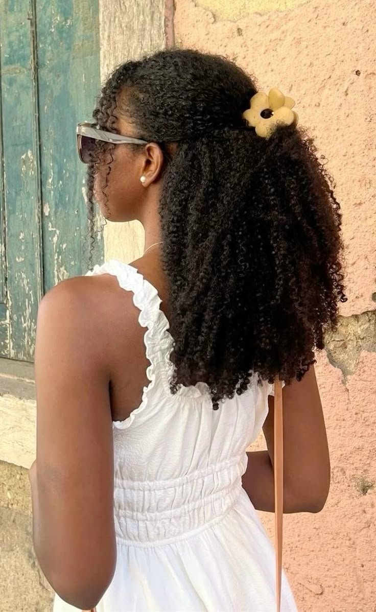 Cabelo cacheado solto com prendedor, mostrando penteado sem tração e vestido branco.