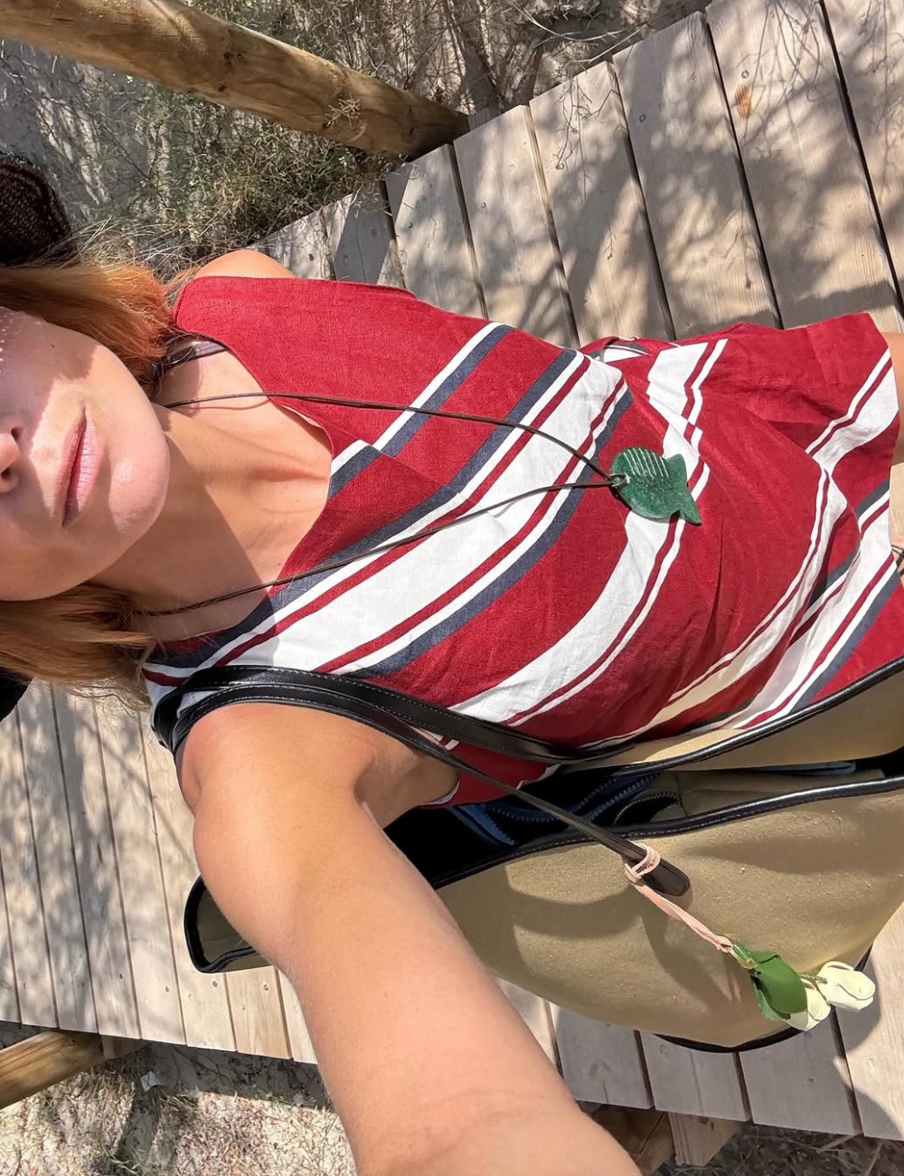 Pessoa em uma passarela de madeira, usando chapéu e blusa listrada, representa o clima do verão 2026.