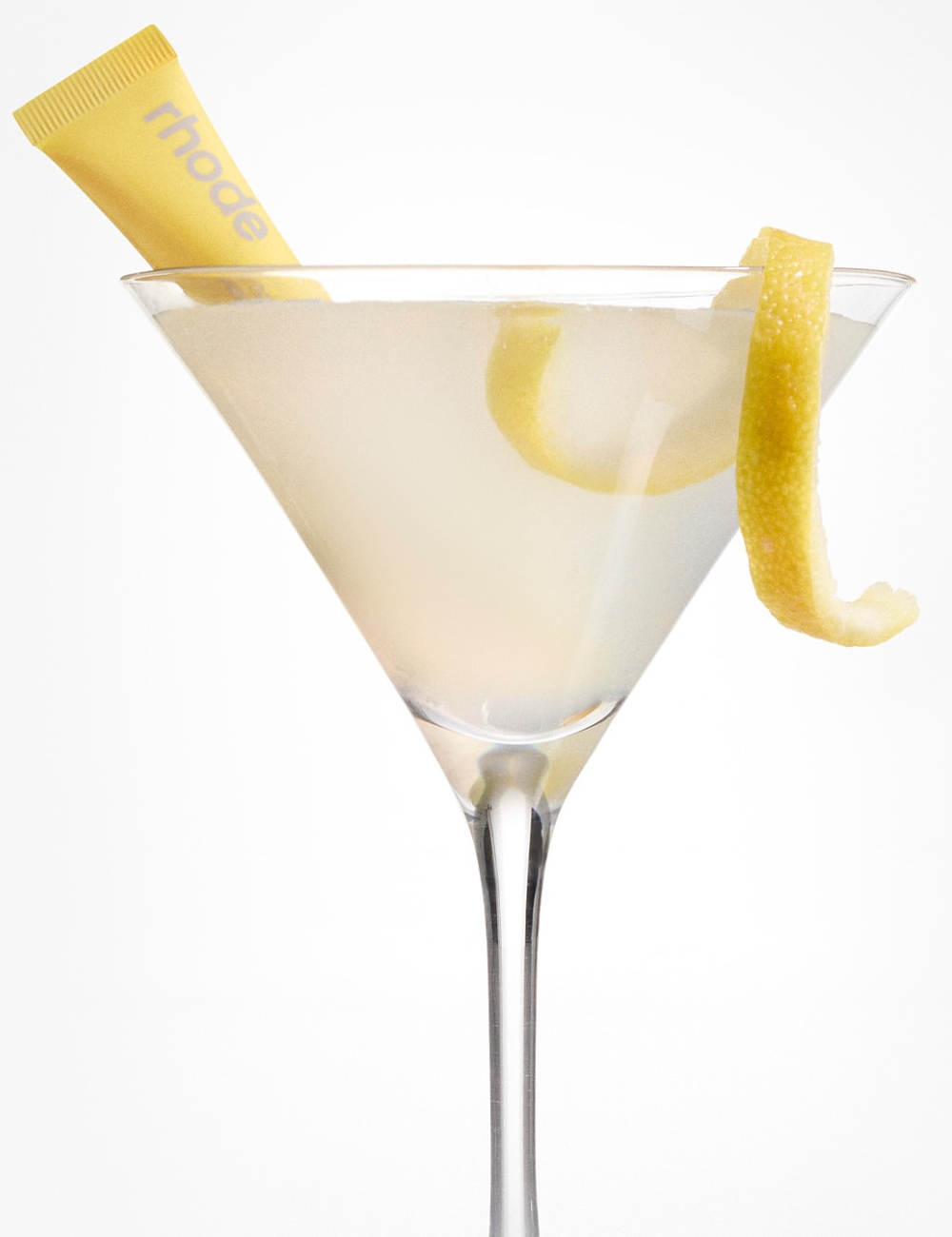 Coquetel estiloso com casca de limão e tubo amarelo decorativo, combinando moda e sofisticação.