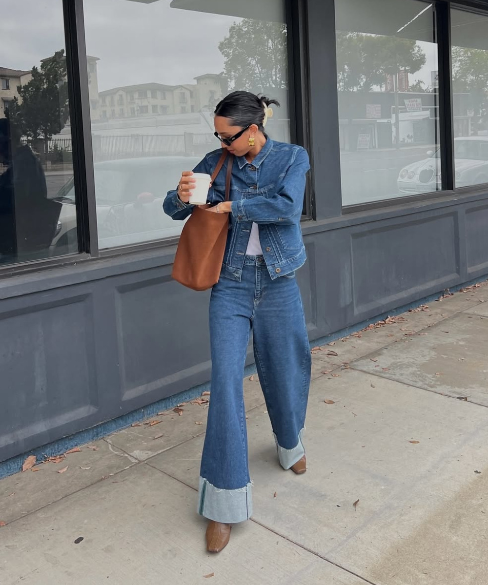 Pessoa usando conjunto jeans e segurando café. Calça flare, tendência na moda urbana.