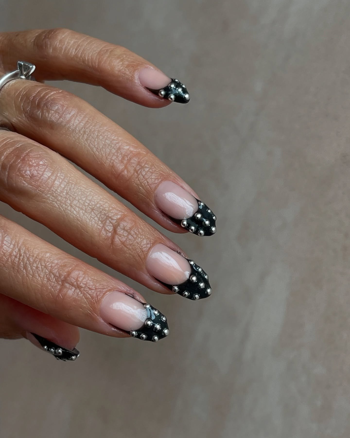Unhas com nail arts estilosas em preto com detalhes de miçangas prateadas.