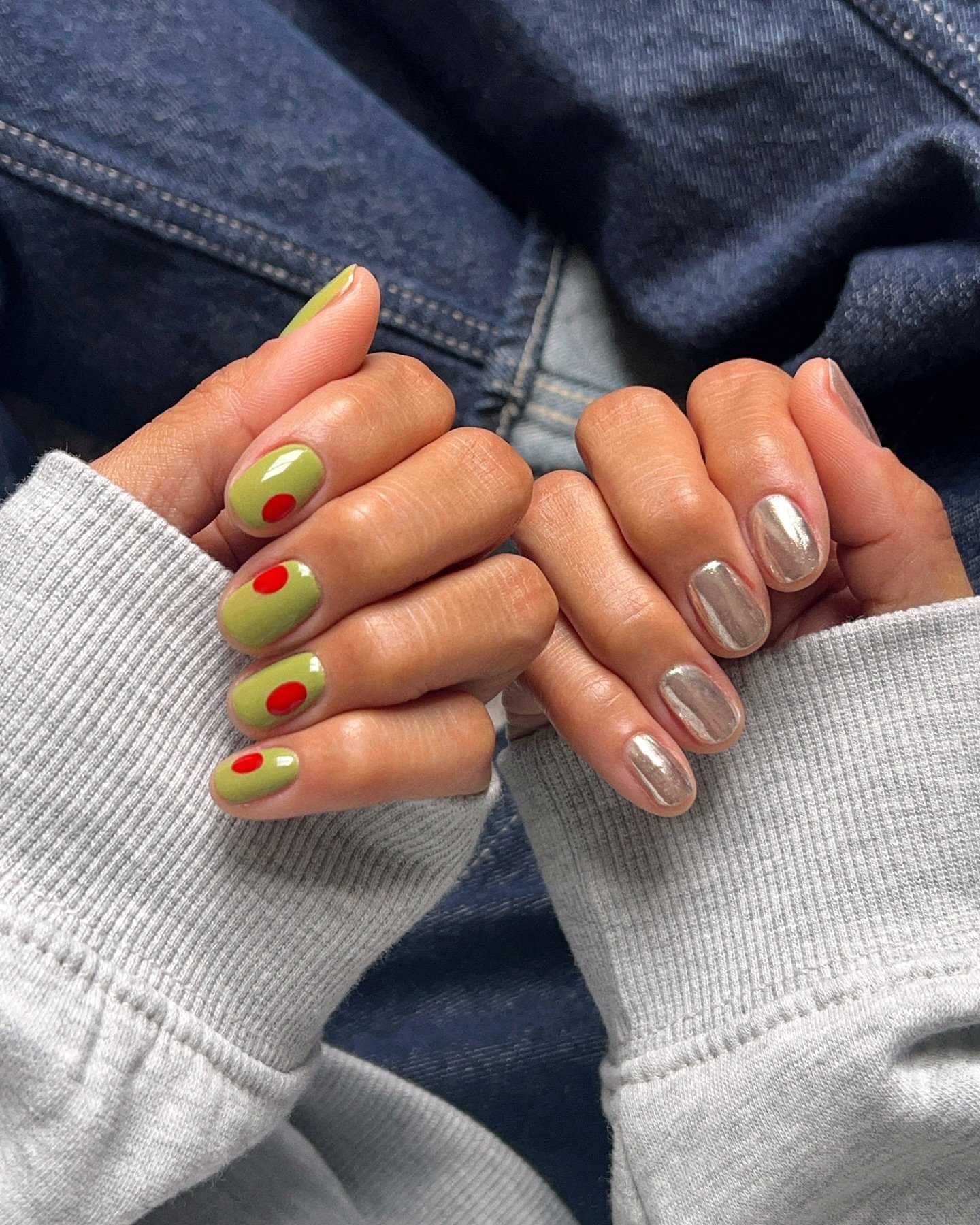 Unhas com nail arts estilosas: verde com círculos vermelhos e prata metálico.